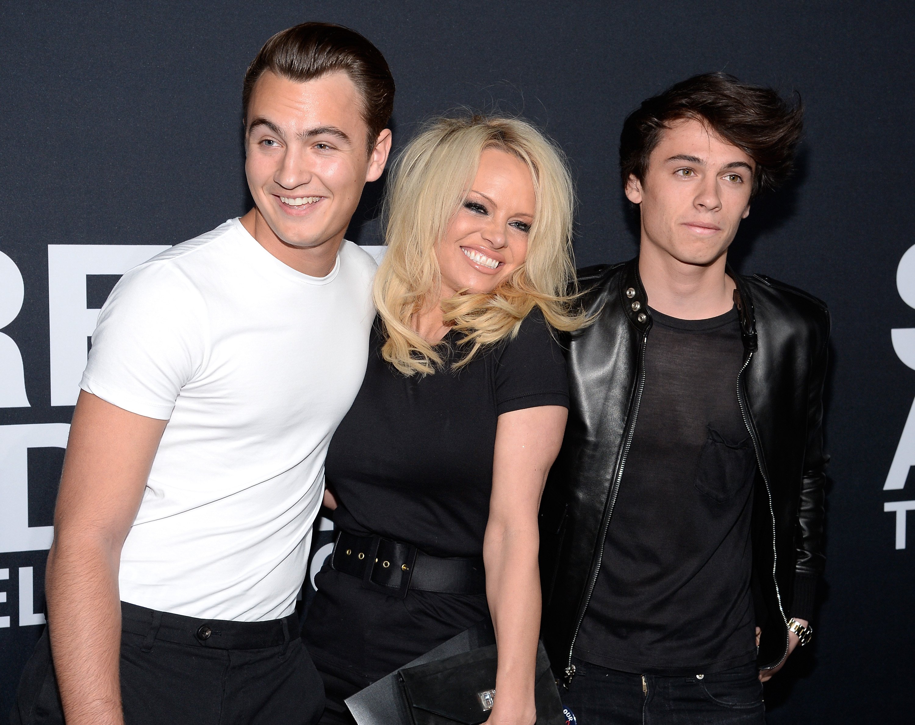 Pamela Anderson (center) and her sons Brandon Lee (L) and Dylan Lee attend the Saint Laurent show at The Hollywood Palladium on February 10, 2016, in Los Angeles, California. | Source: Getty Images.