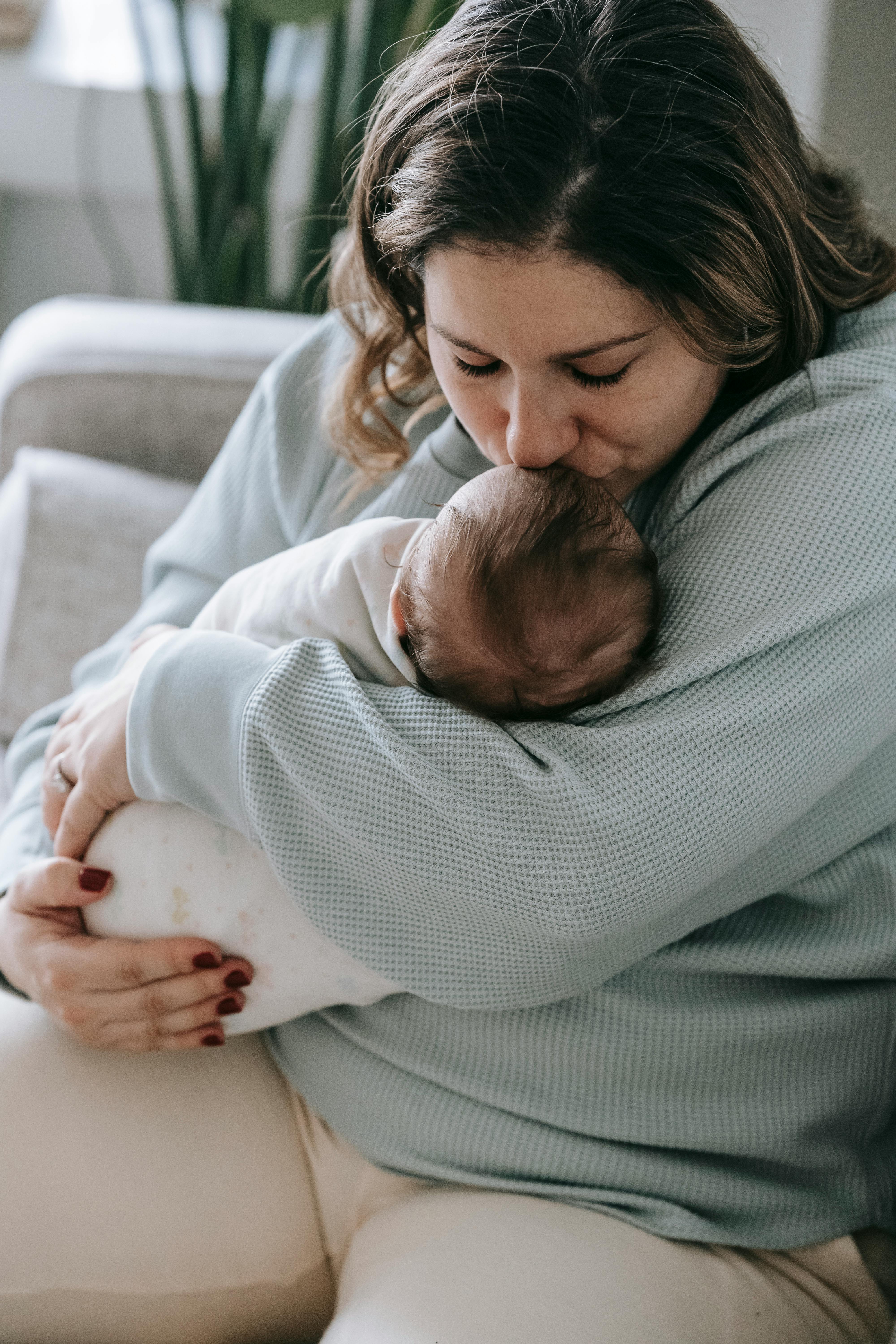 A woman kissing her baby's forehead | Source: Pexels
