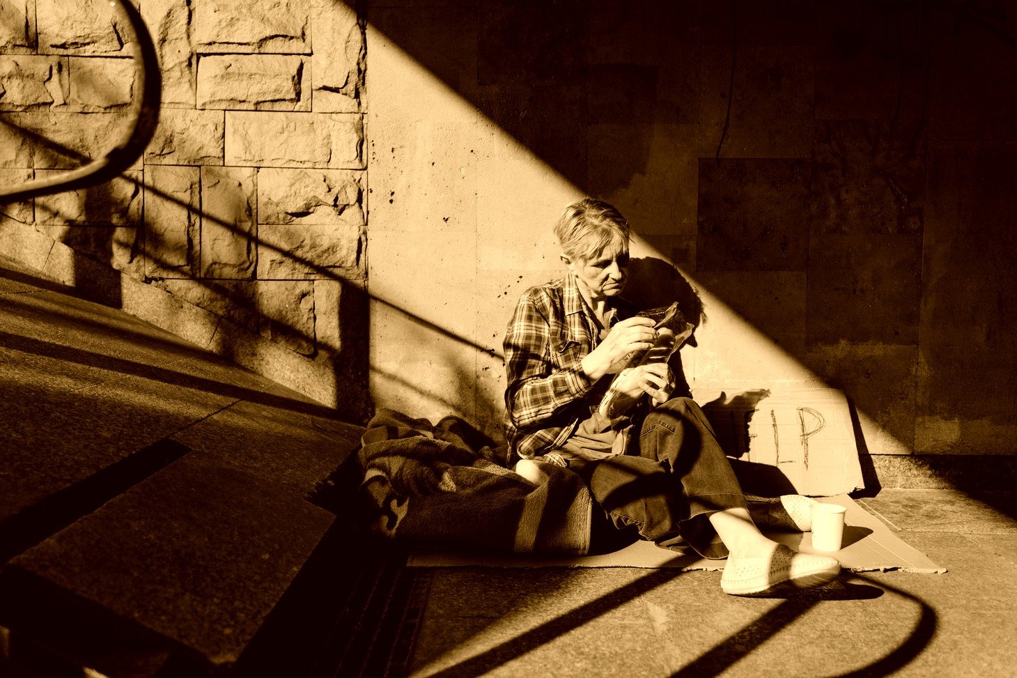 Mujer indigente sentada al pie de una escalera pidiendo ayuda. | Foto: Pexels