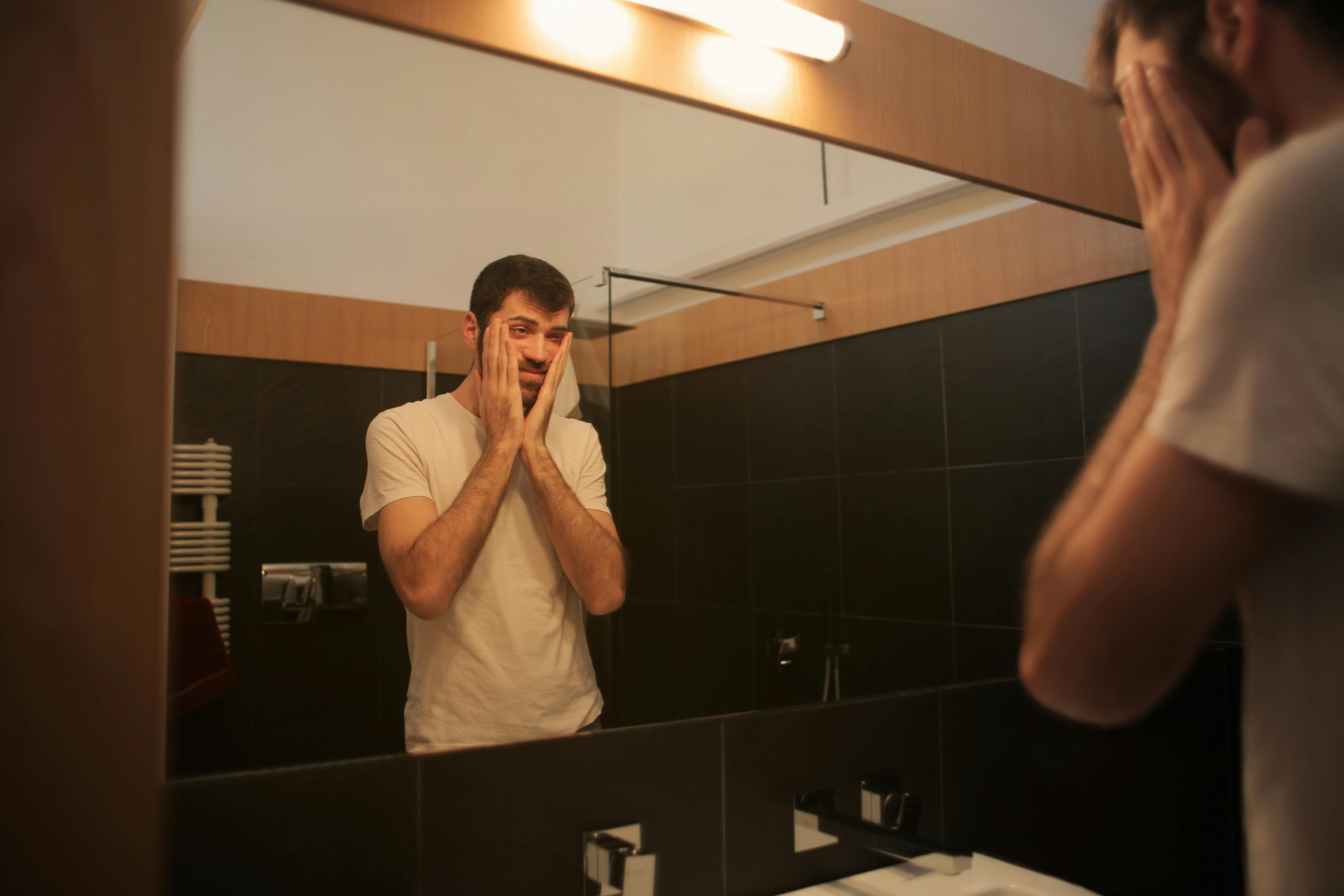A frustrated man looking at himself in a mirror | Source: Pexels