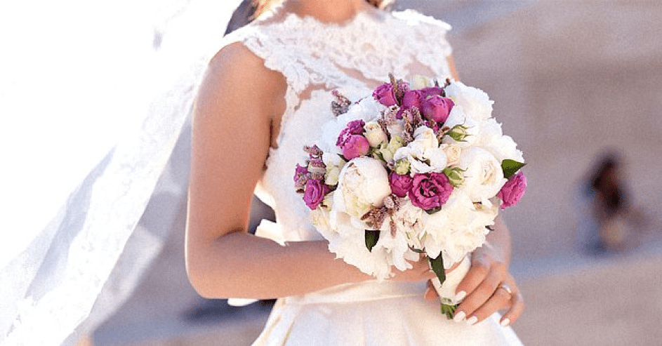 Eine Braut im weißen Kleid hält den Brautstrauß. | Quelle: Shutterstock 