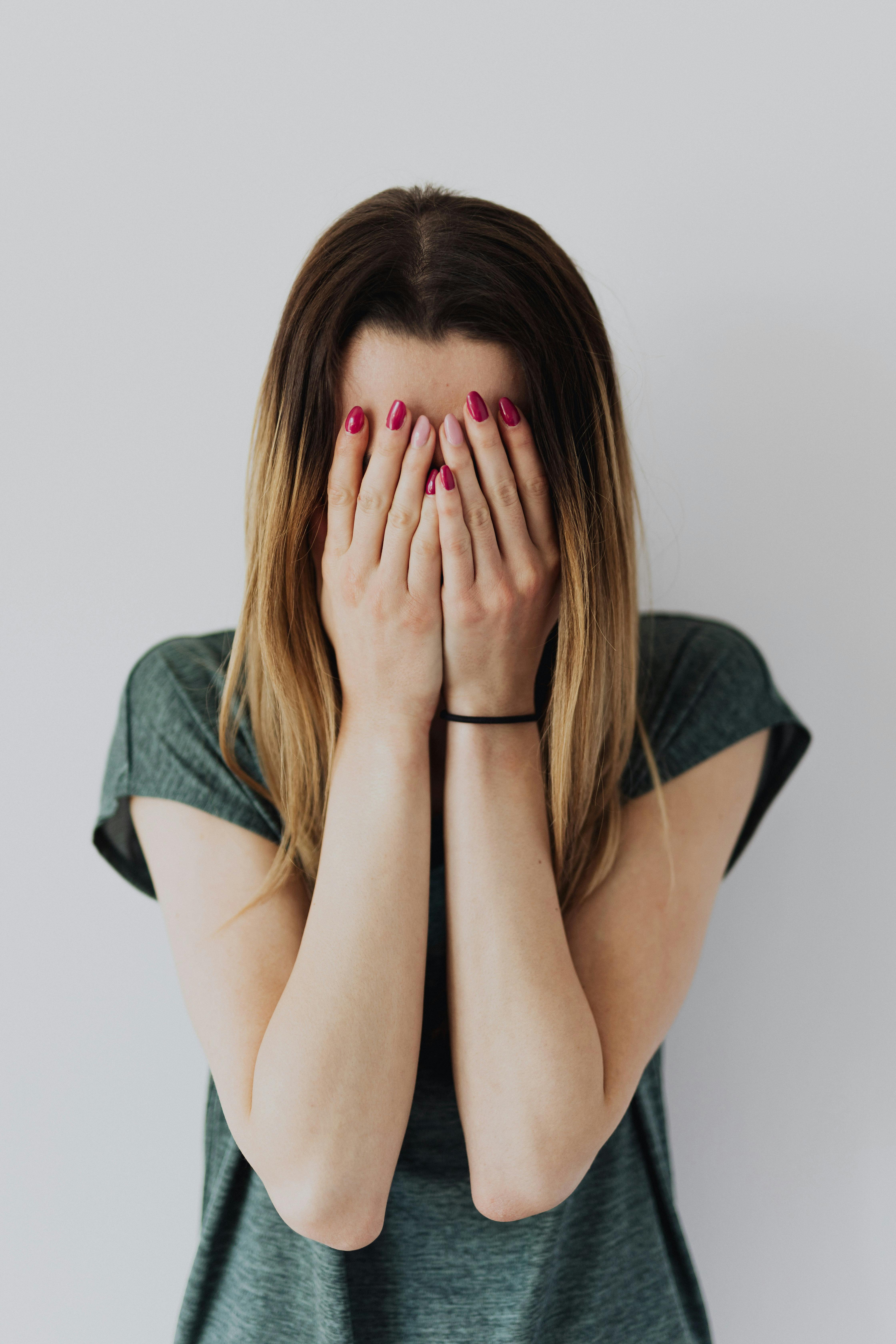 A young woman covering her face with her hands | Source: Pexels