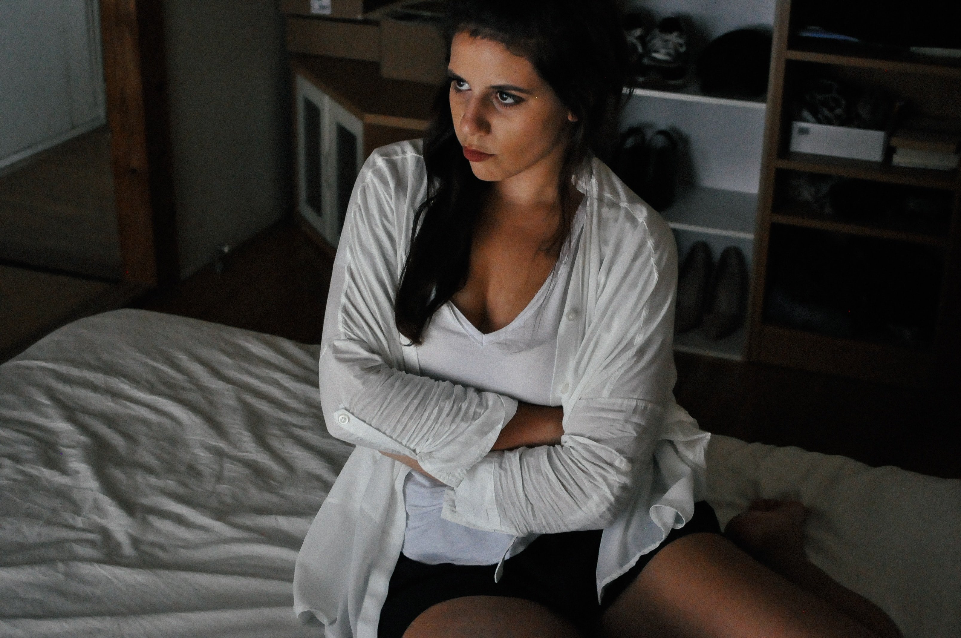 Photo of an upset woman sitting and folding her arms on the bed. | Photo: Upsplash