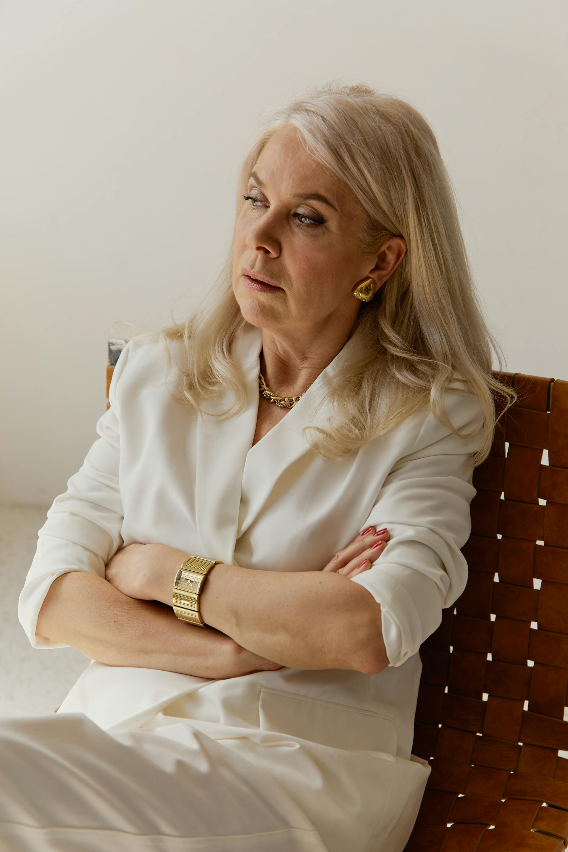 A serious-looking senior woman crossing her arms and sitting on a chair | Source: Pexels