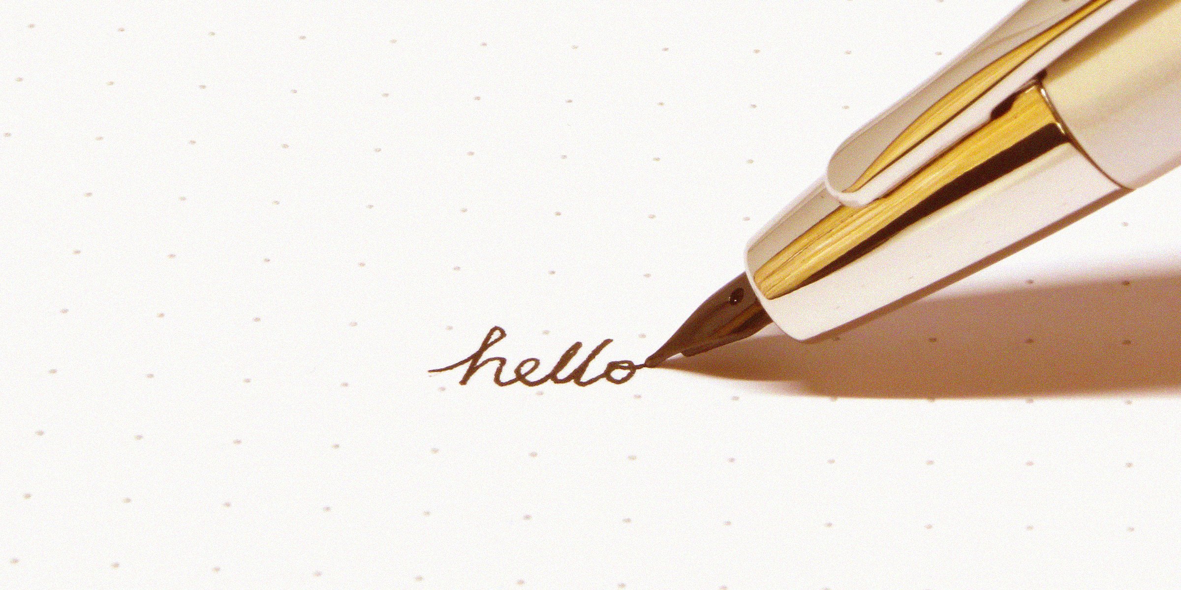 Unsplash | An individual writing 'hello' in calligraphy,