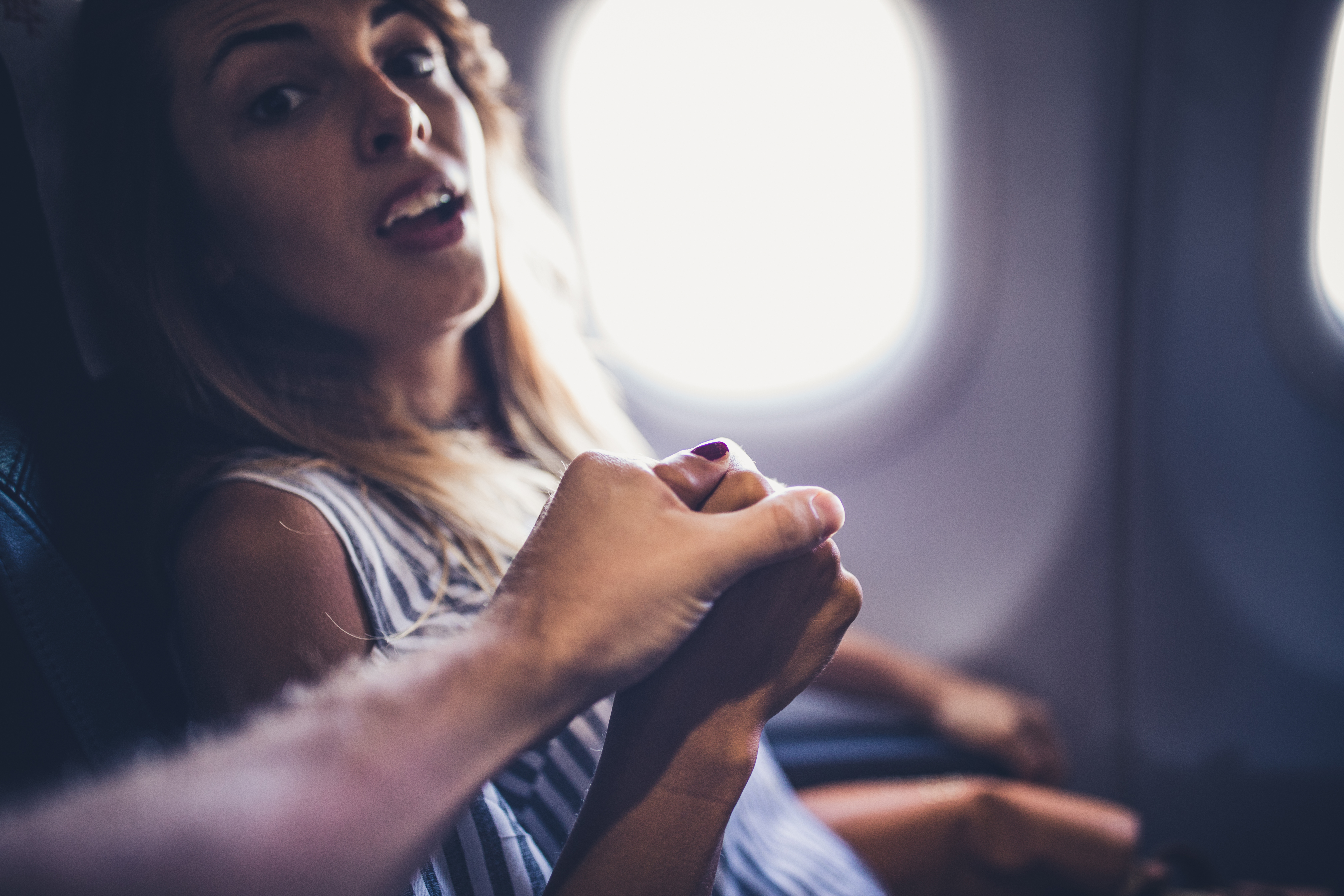 Husband holds scared wife's hand on a plane | Source: Getty Images