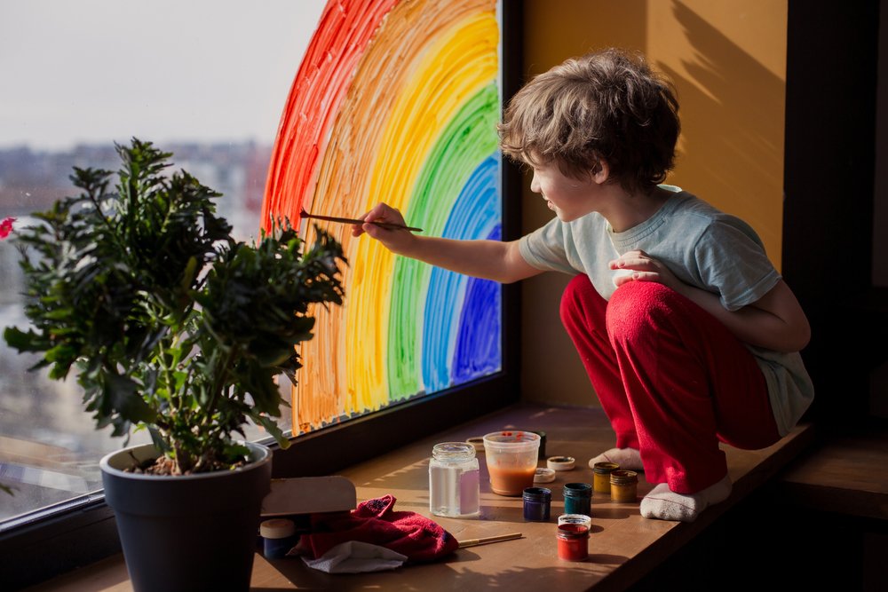 A child drawing a rainbow on a window | Photo: Shutterstock/Da Antipina