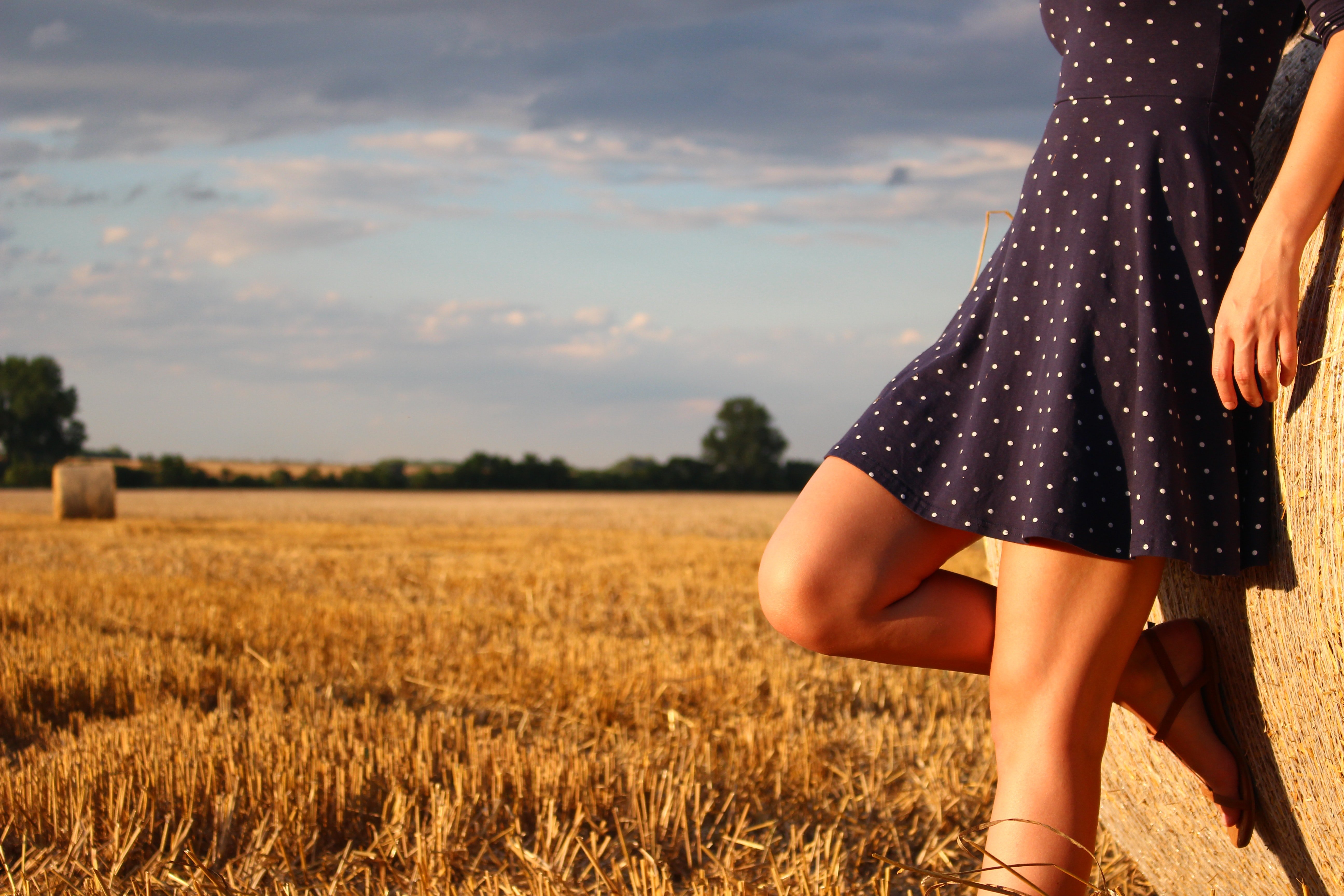 Pictured - A woman standing in a field on a sunny day wearing a blue polka dot dress | Source: Pexels 