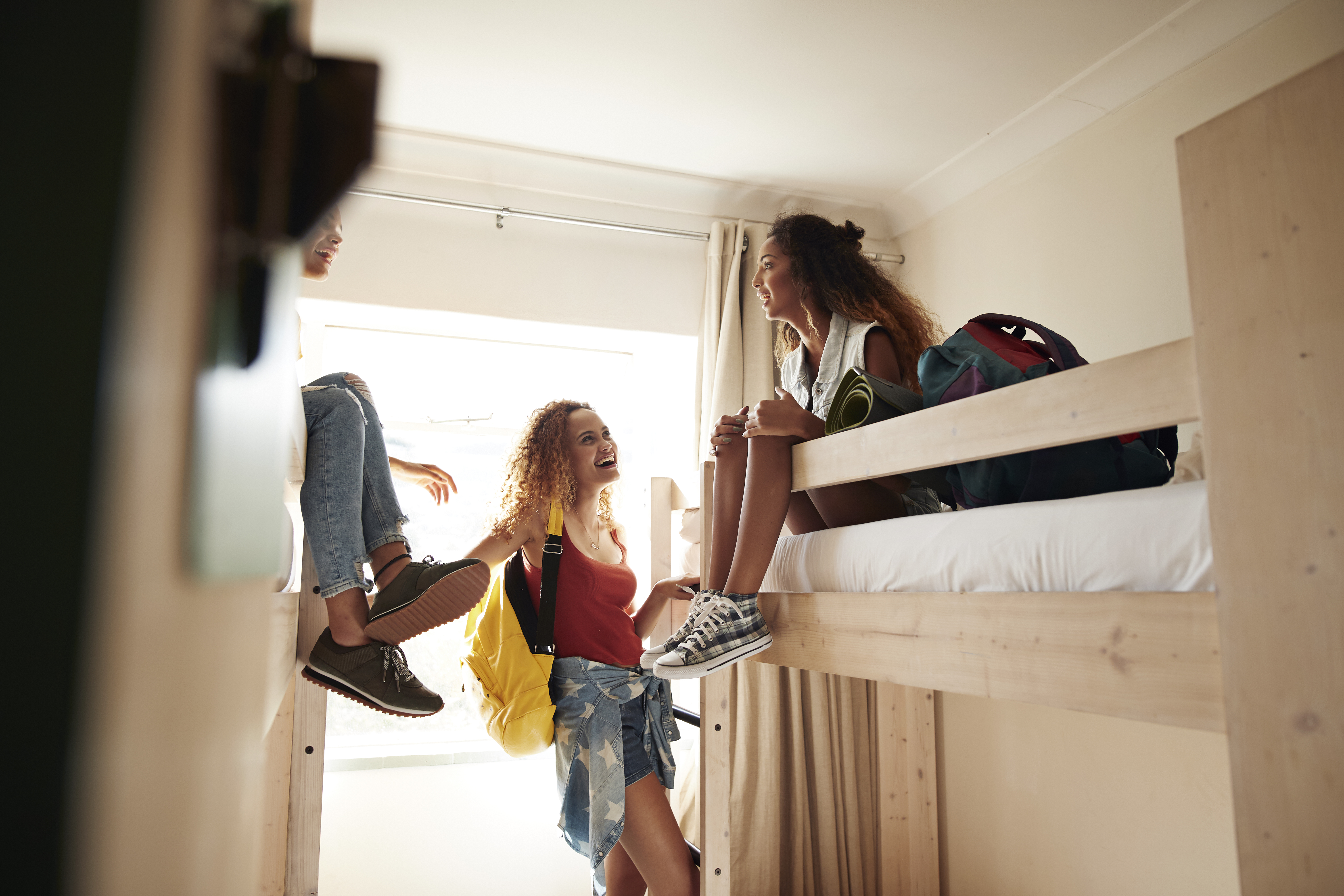 Young women sitting on bunk beds in dorm room | Source: Getty Images