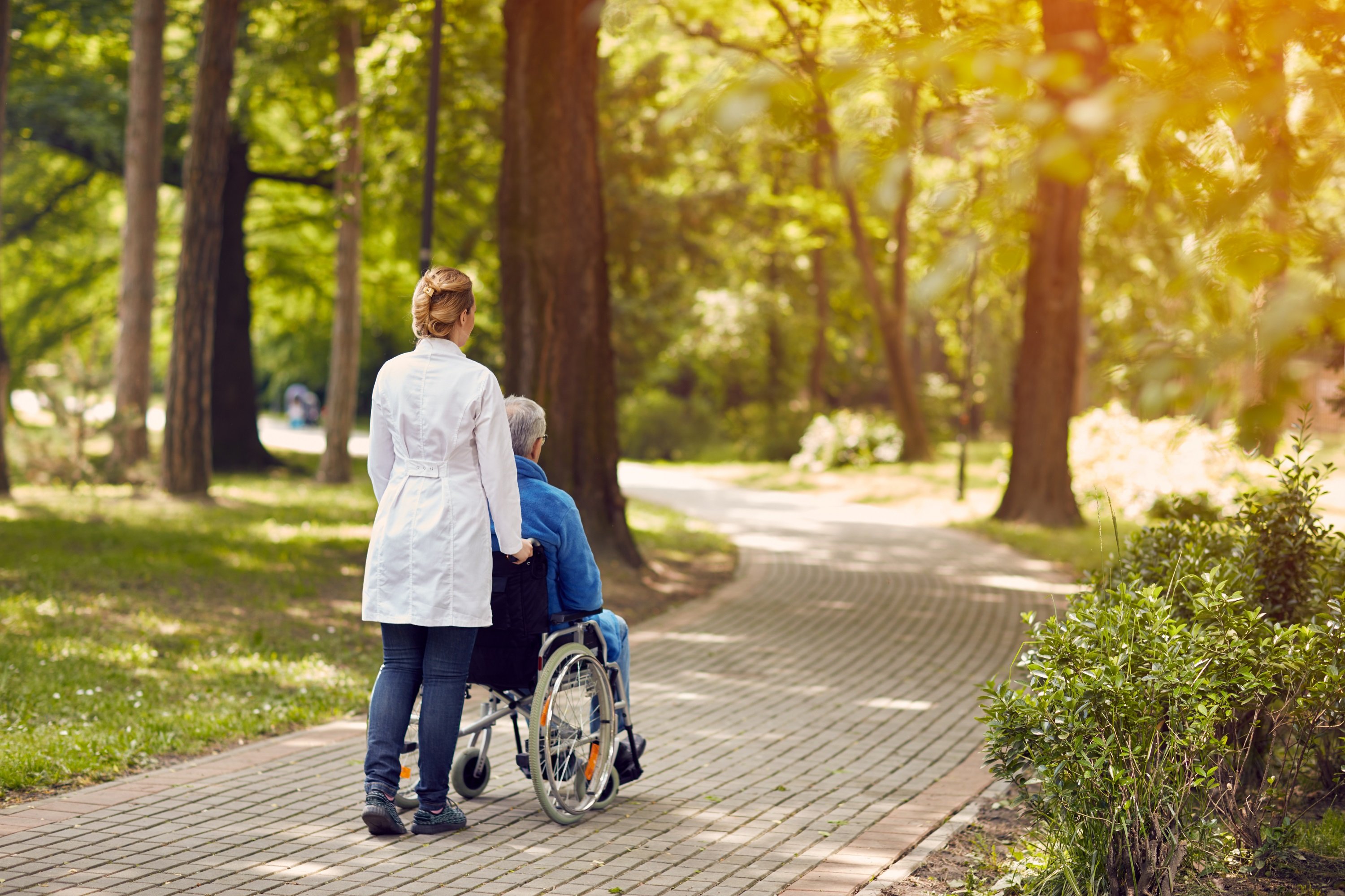 Hombre en silla de ruedas de paseo con cuidadora. | Foto: Shutterstock