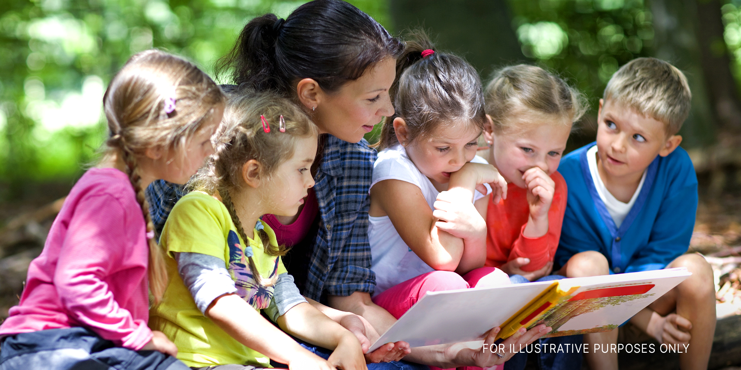 Woman reading a book to young children | Source: Shutterstock