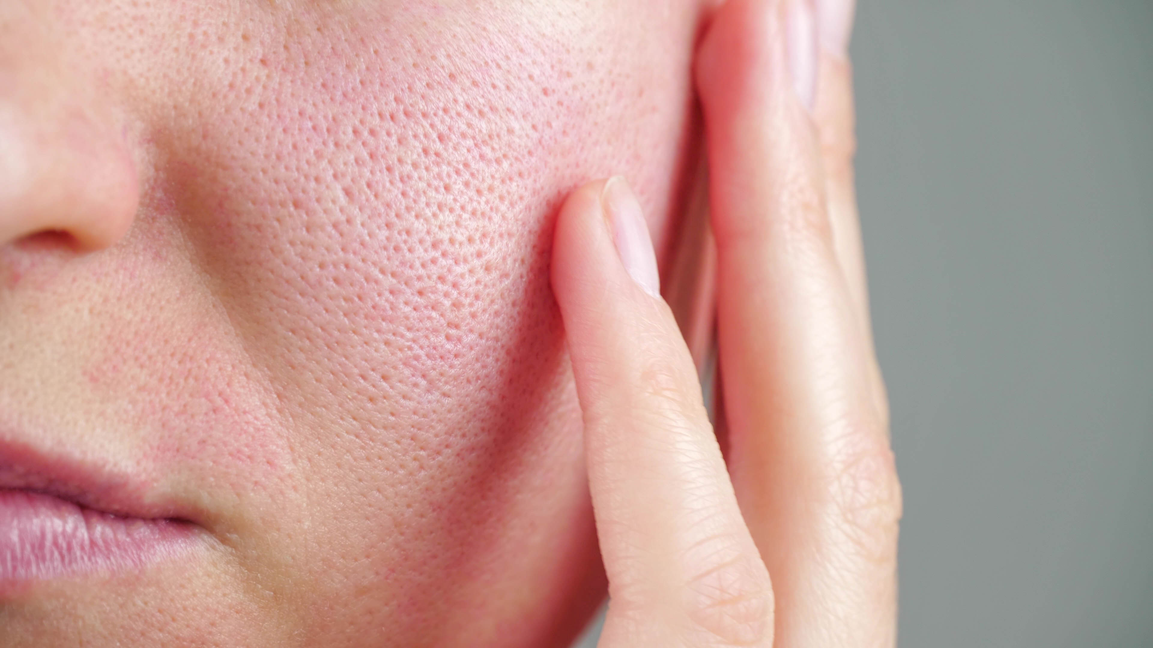 A woman with visible pores touching her cheek | Source: Shutterstock