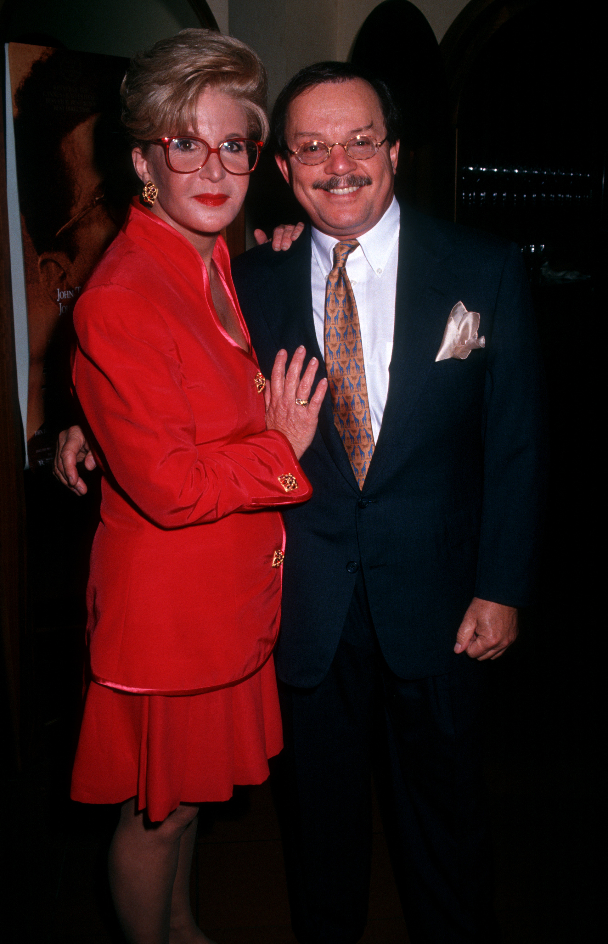 Sally Jessy Raphael and her husband, Karl Soderlund, attend the First Annual Joan Rivers Oscar Night Party at San Domenico in New York City on March 30, 1992. Raphael wears a bold red skirt suit with gold accents and her signature red glasses, standing beside Soderlund in a classic dark suit and tie.