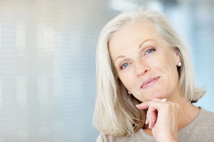 Portrait en gros plan d'une belle femme d'âge mûr, la main sur le menton vous donnant un sourire chaleureux. | Photo : Getty Images