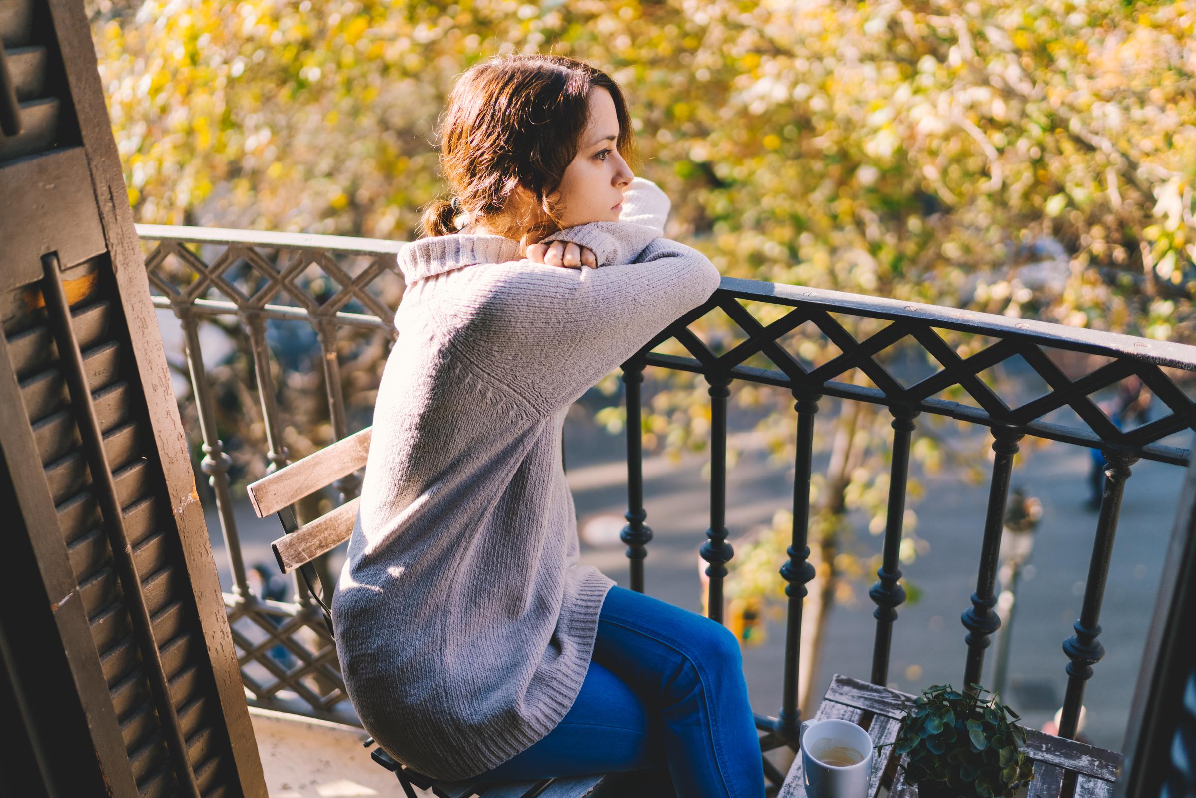 A woman sitting at a balcony, leaning on the railing | Source: Getty Images