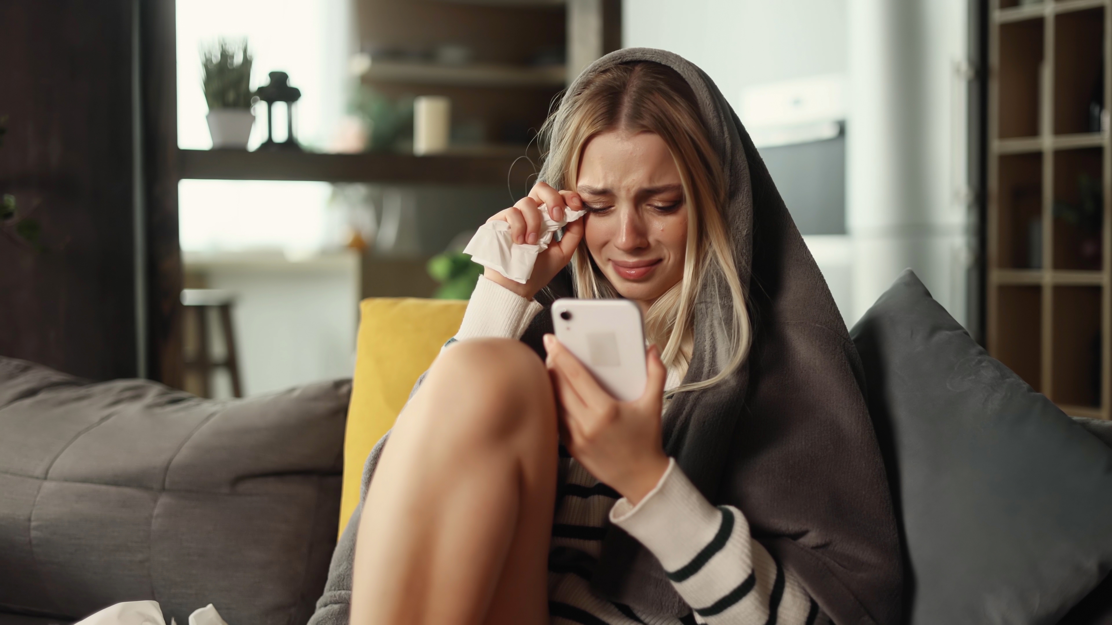 A woman crying while looking at her phone | Source: Shutterstock