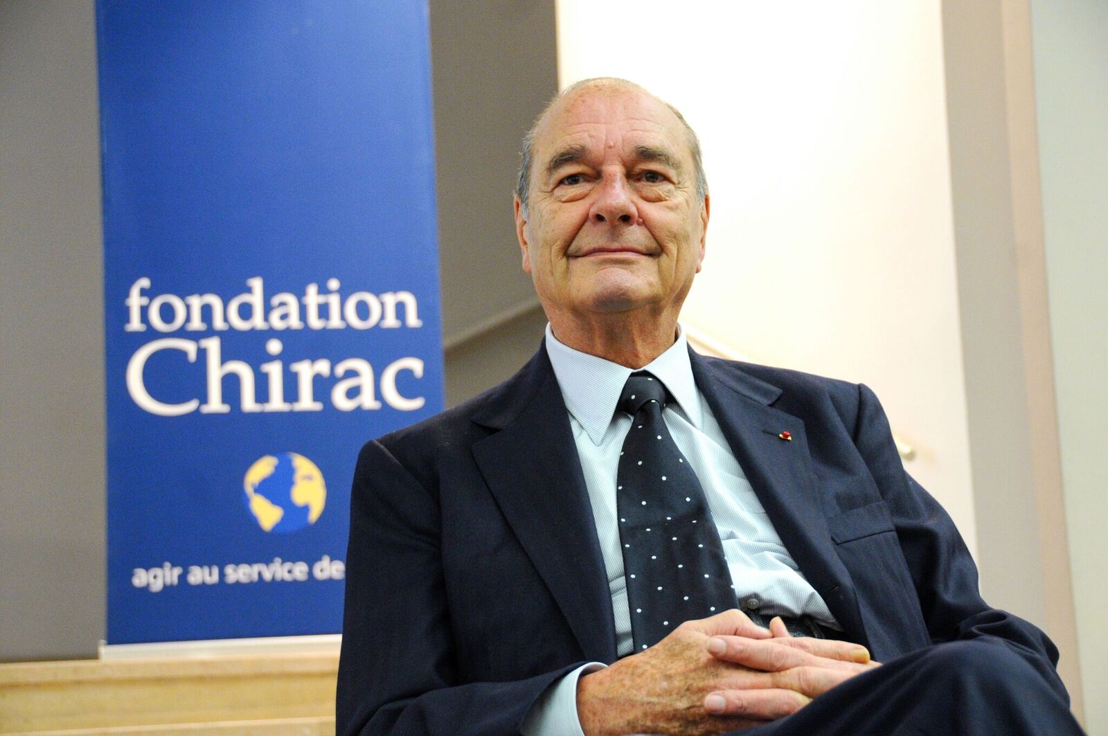 Portrait de Jacques Chirac qui pose devant une affiche de la Fondation Chirac. | Photo : GettyImage