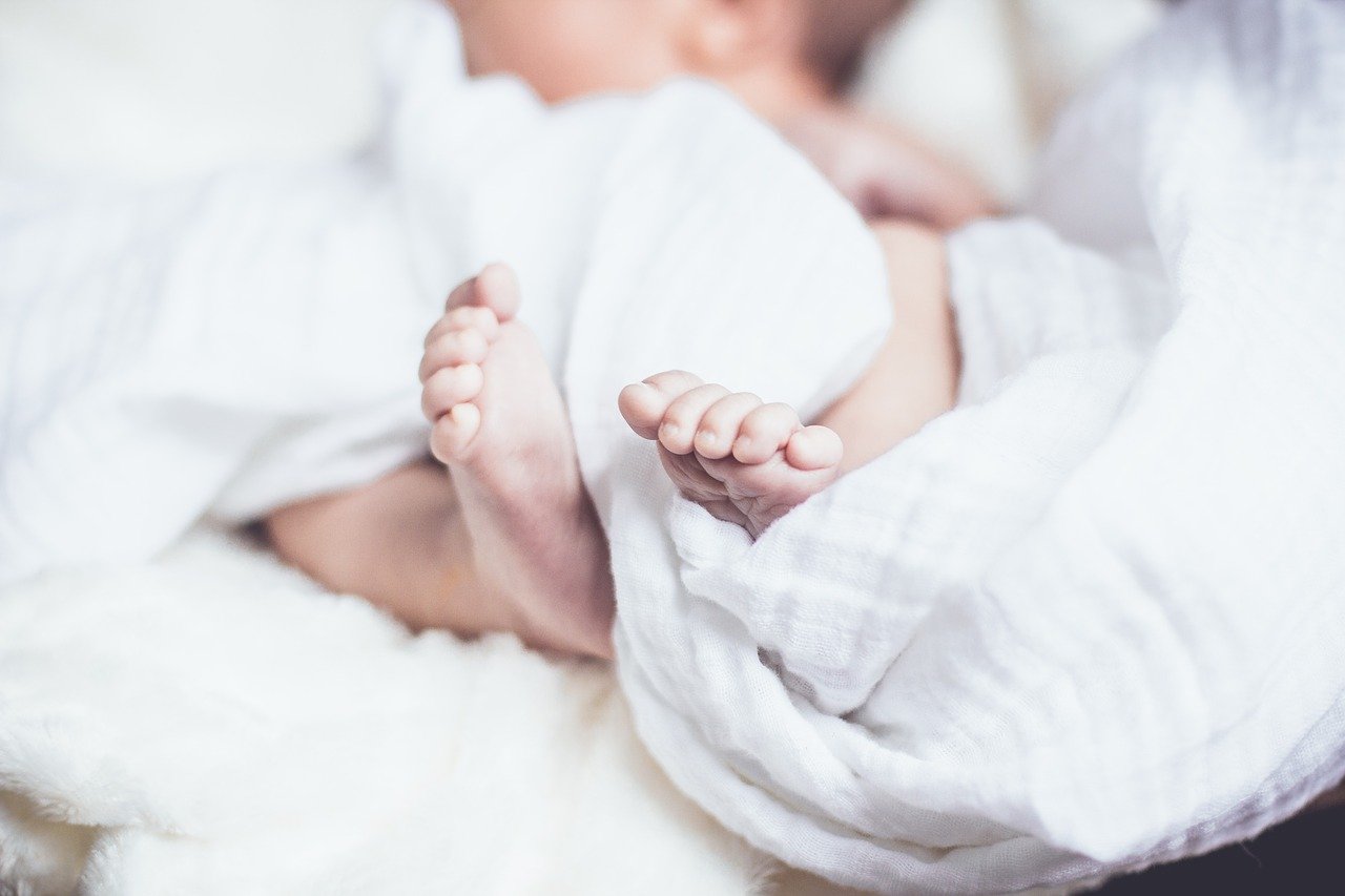 Pies de bebé entre mantas blancas. | Foto: Pixabay