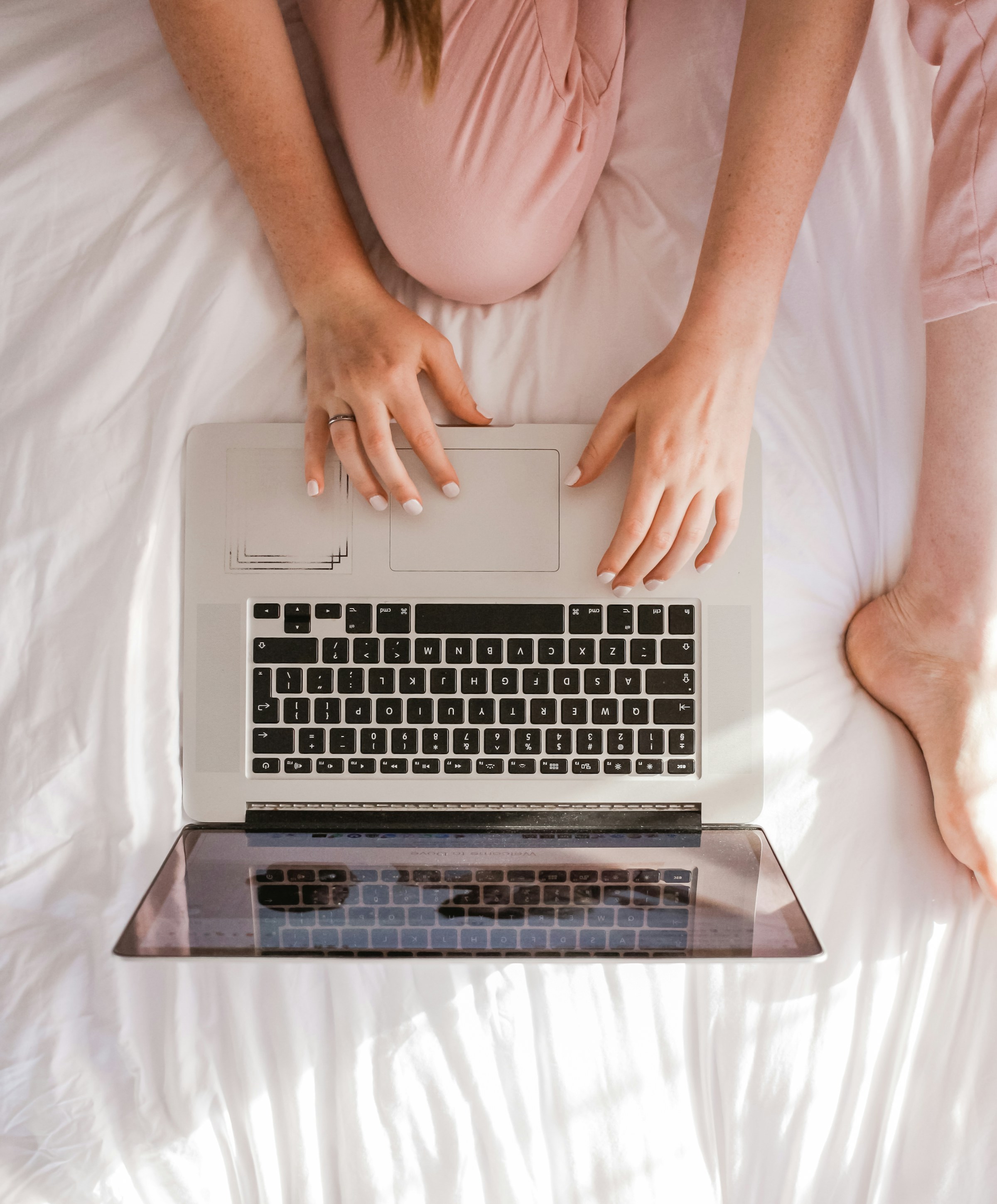 A close-up of a woman using her laptop in bed | Source: Unsplash