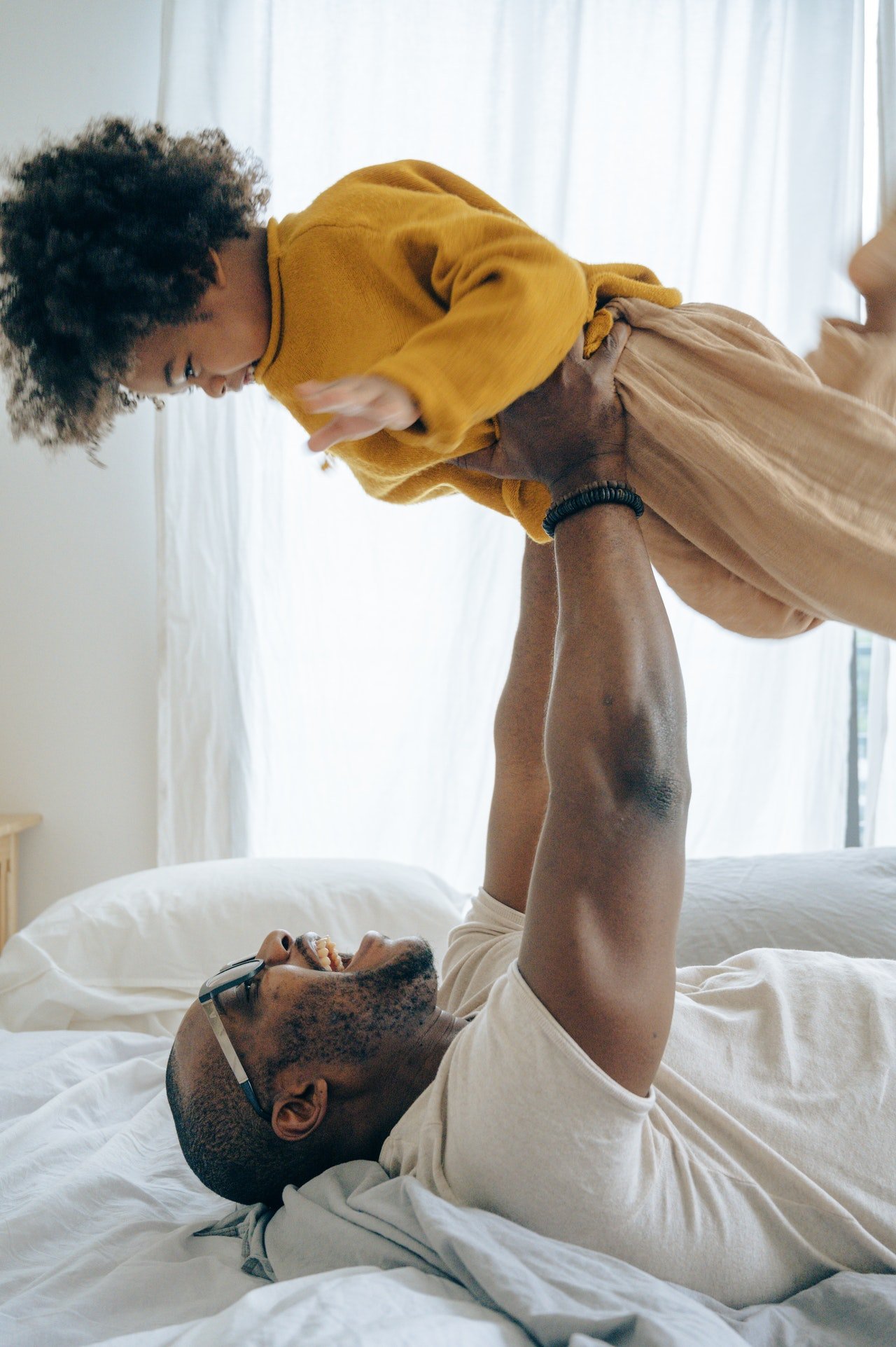 Father lifting his son on the bed | Source: Pexels