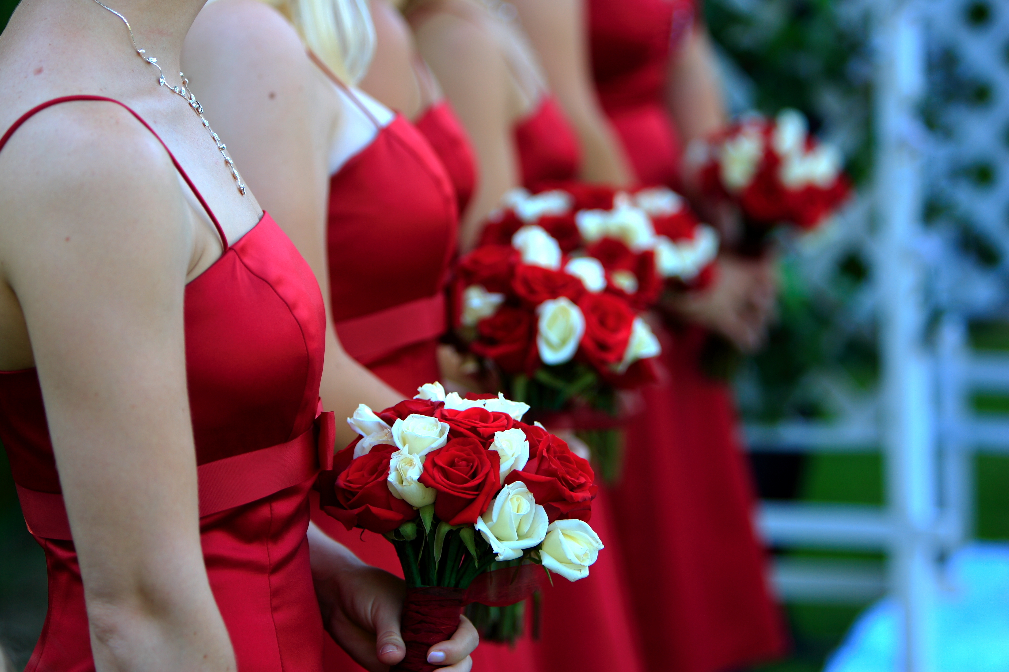 A row of bridesmaids wearing read dresses and holding flower bouquets | Source: Shutterstock