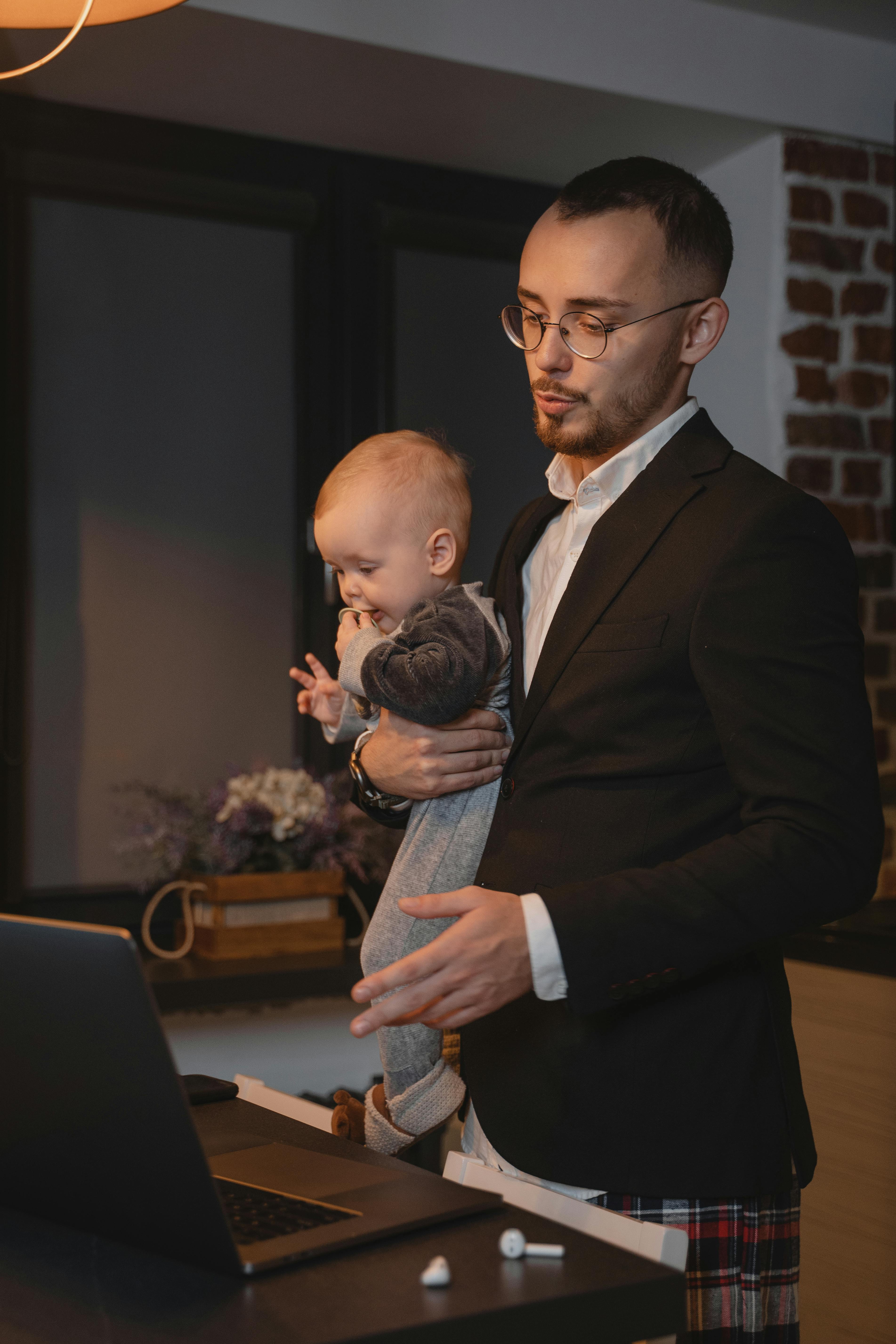 A father carrying a baby while on his laptop | Source: Pexels