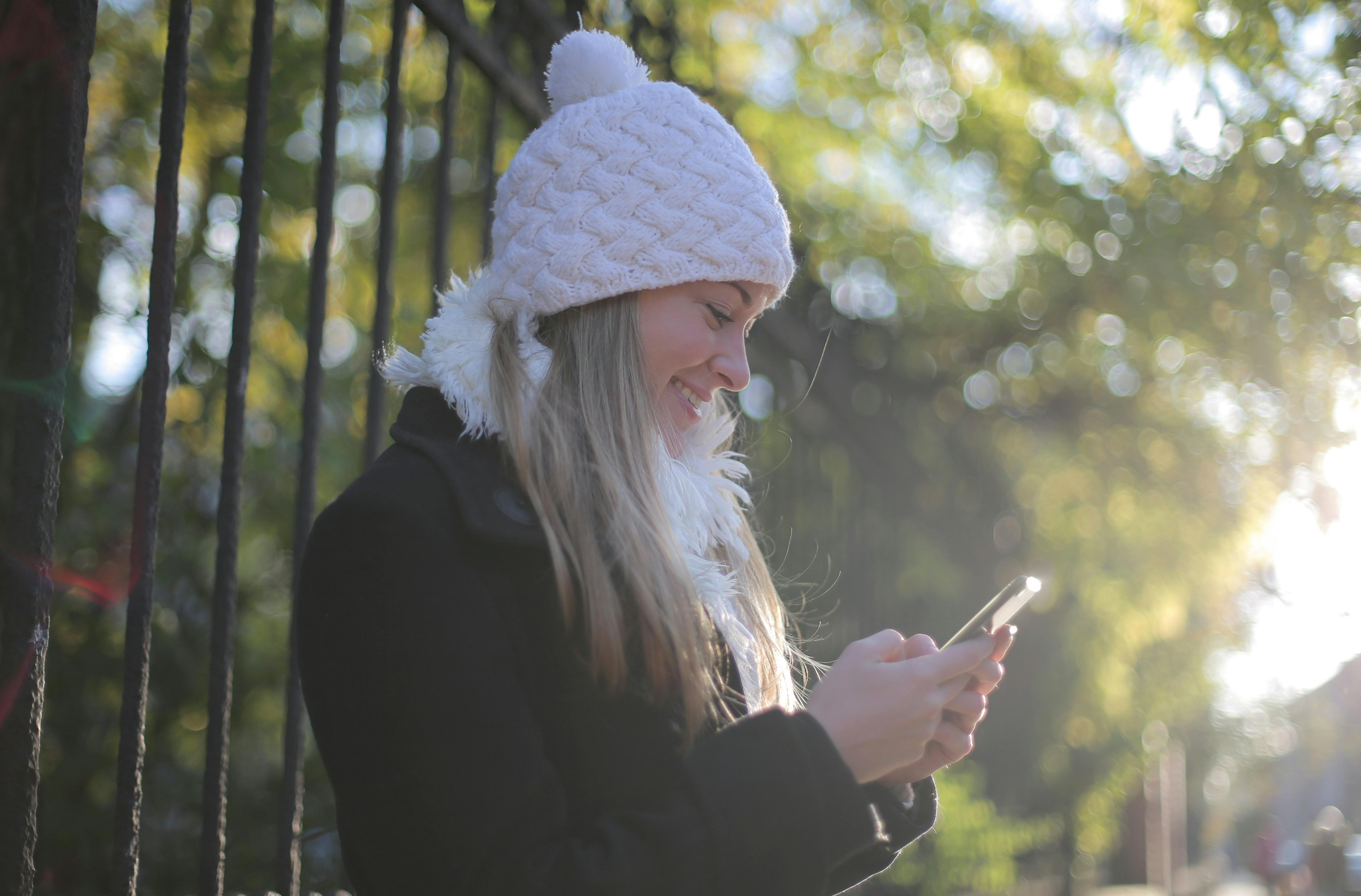 A woman smiling while looking at her phone | Source: Pexels