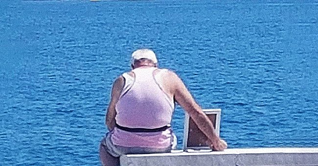 Giuseppe Giordano istuu meren edessä kehystetyn kuvan kanssa edesmenneestä vaimostaan.  │ Lähde: facebook.com/giorgio.moffa.9