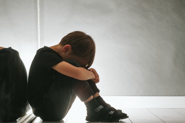 Niño triste sentado en el piso.│Foto: Freepik