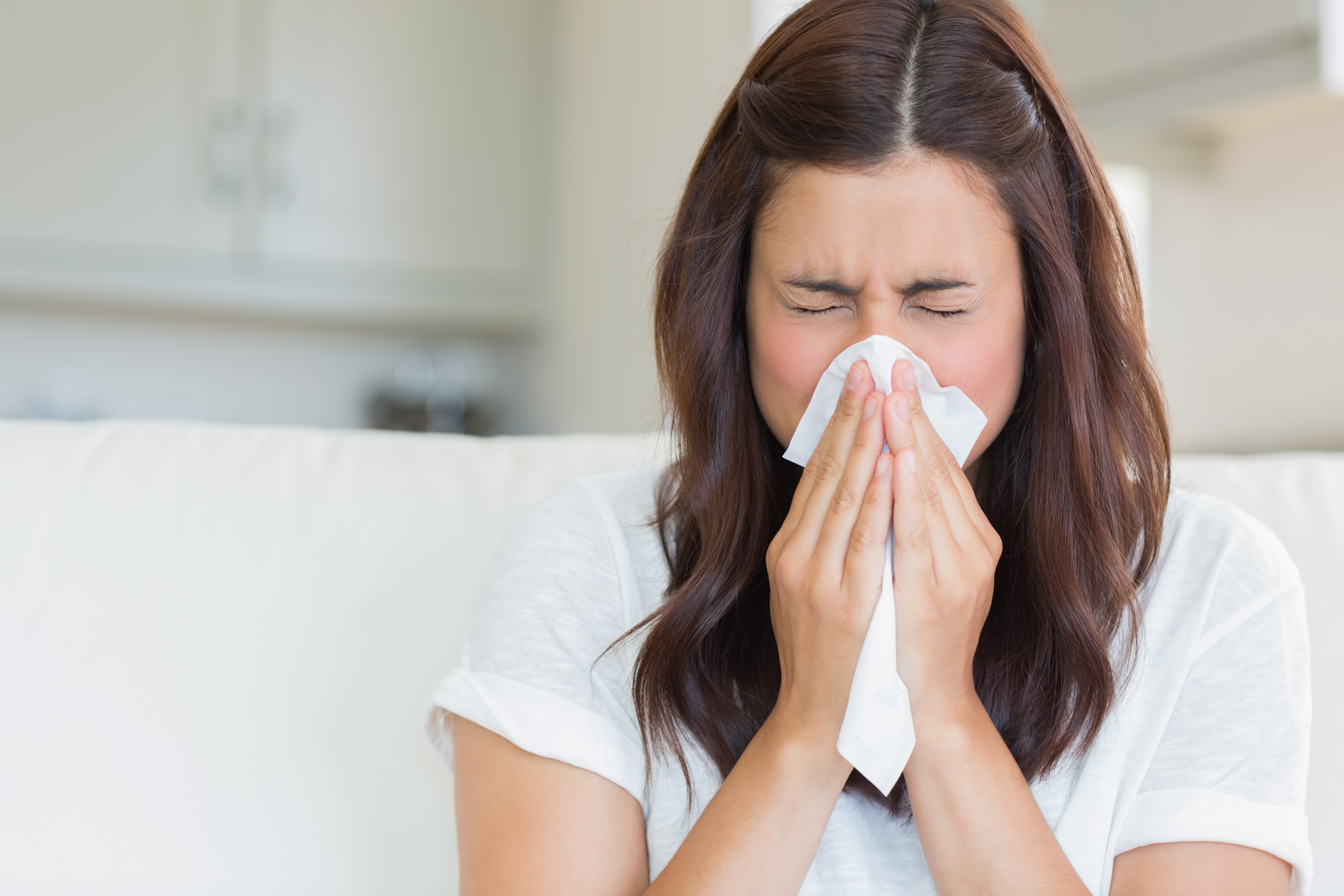 A woman sneezing with a tissue on her nose and mouth | Source: Shutterstock