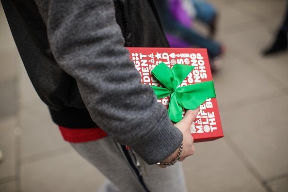 A man carries a gift-wrapped box on Oxford Street in London, England | Photo: Getty Images