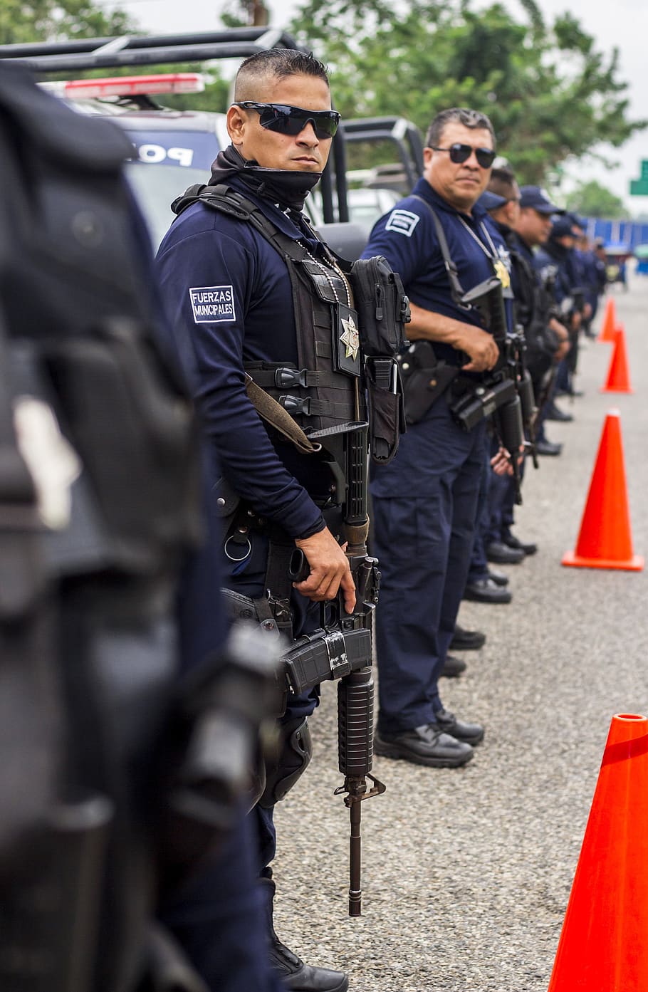 Grupo de oficiales de la policía sosteniendo rifles de asalto junto a varias patrullas. | Foto: PxFuel