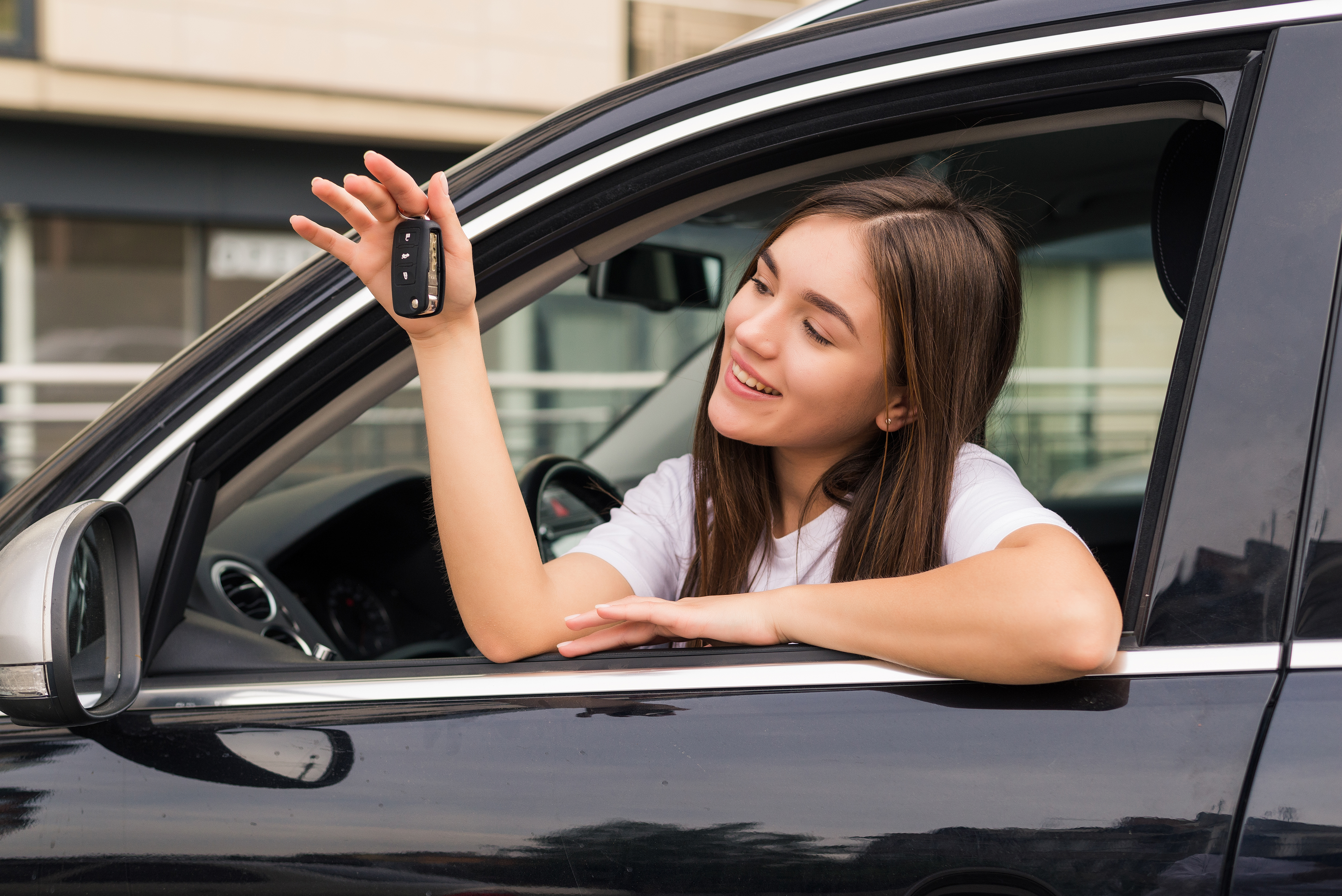 Happy young girl inside a car while holding up her car keys | Source: Freepik