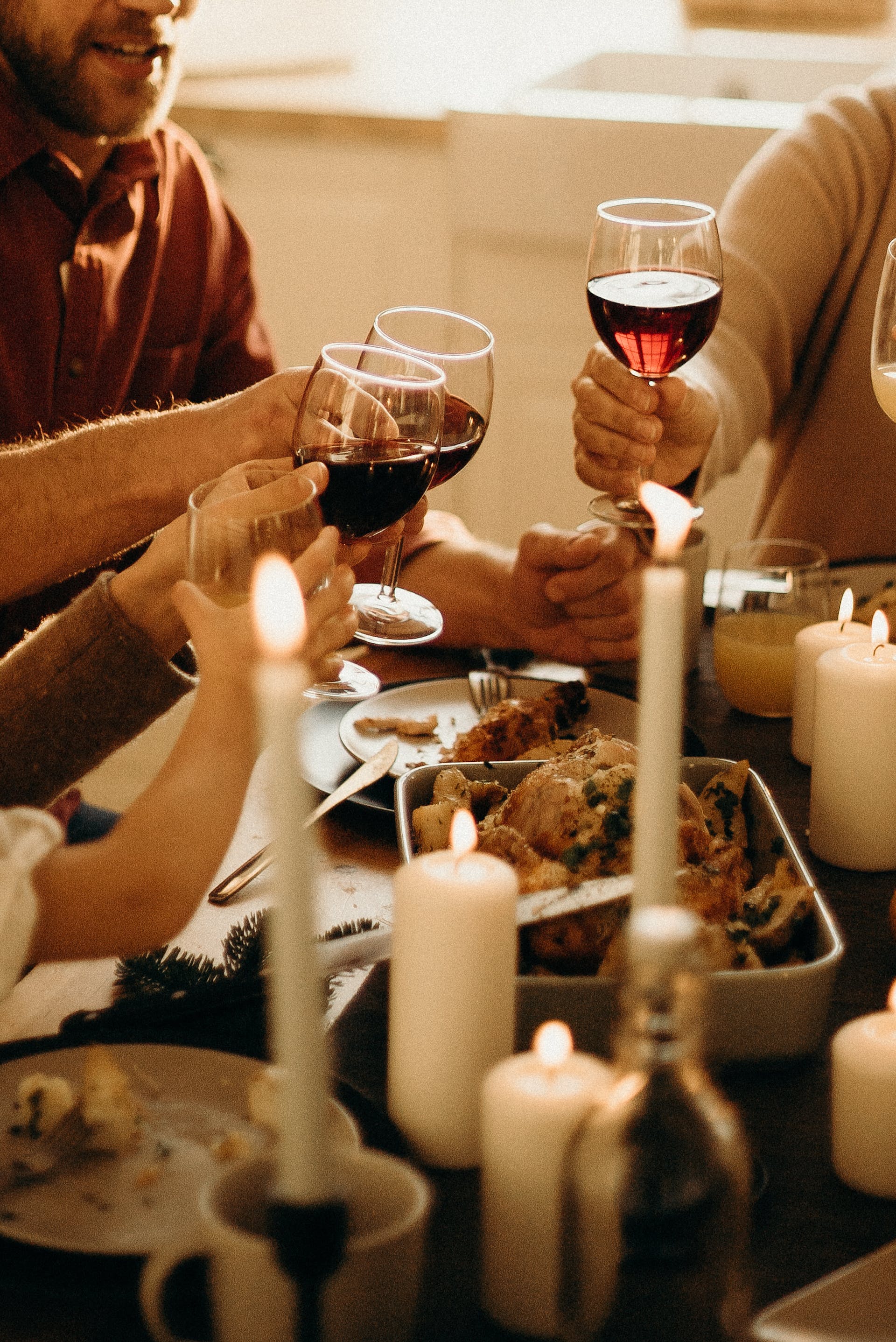 People raising wine glasses at the dinner table | Source: Pexels