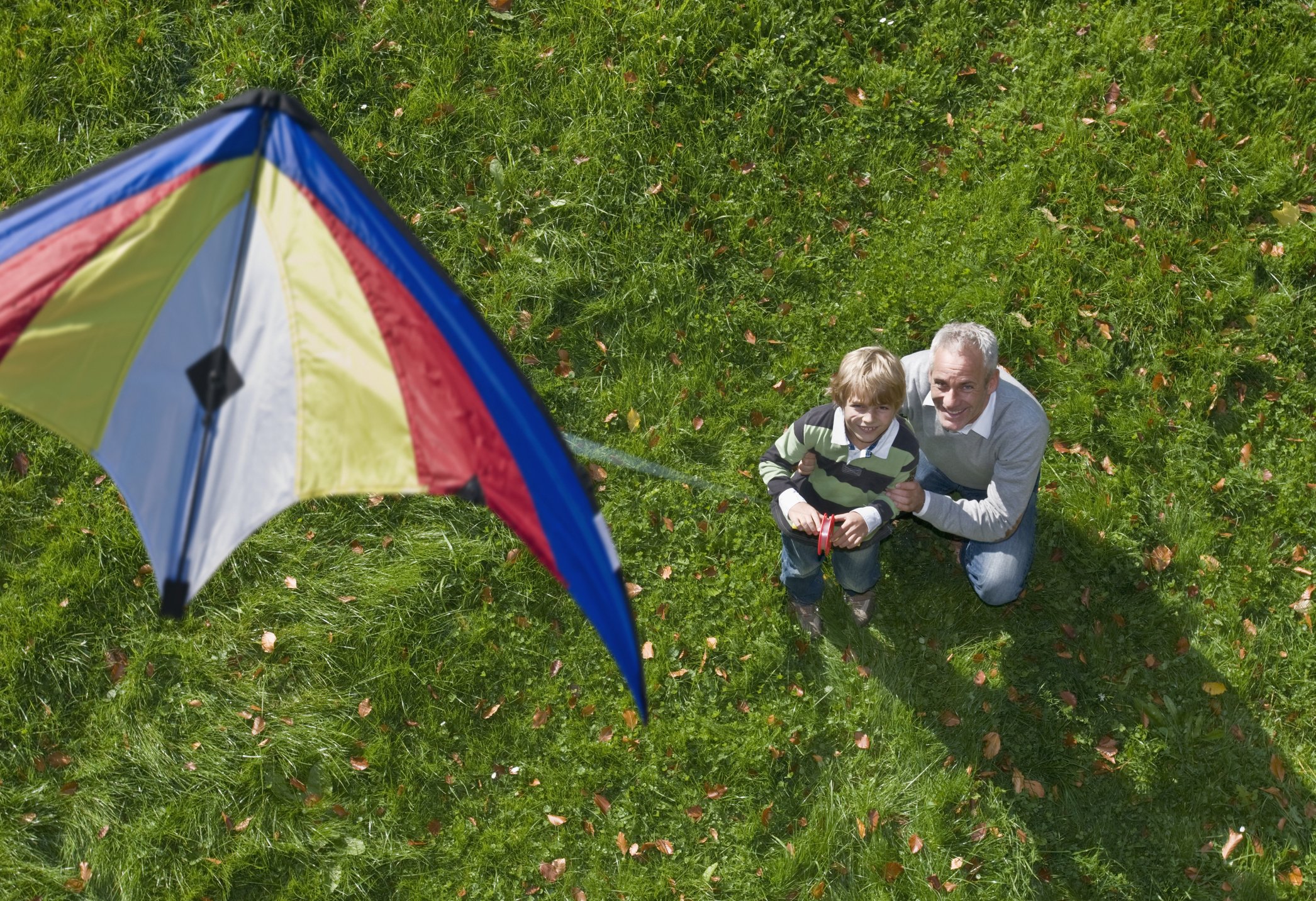A father and a son pictured flying a kite from above. | Photo: Getty Images