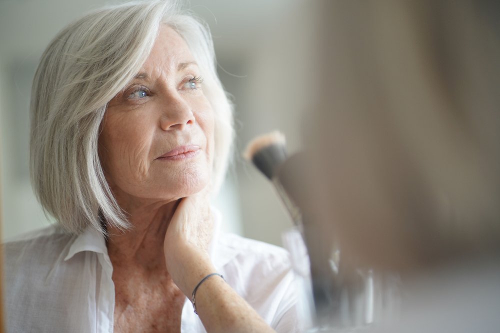 Schöne Frau vor dem Spiegel mit Schminkpinsel. I Quelle: Shutterstock