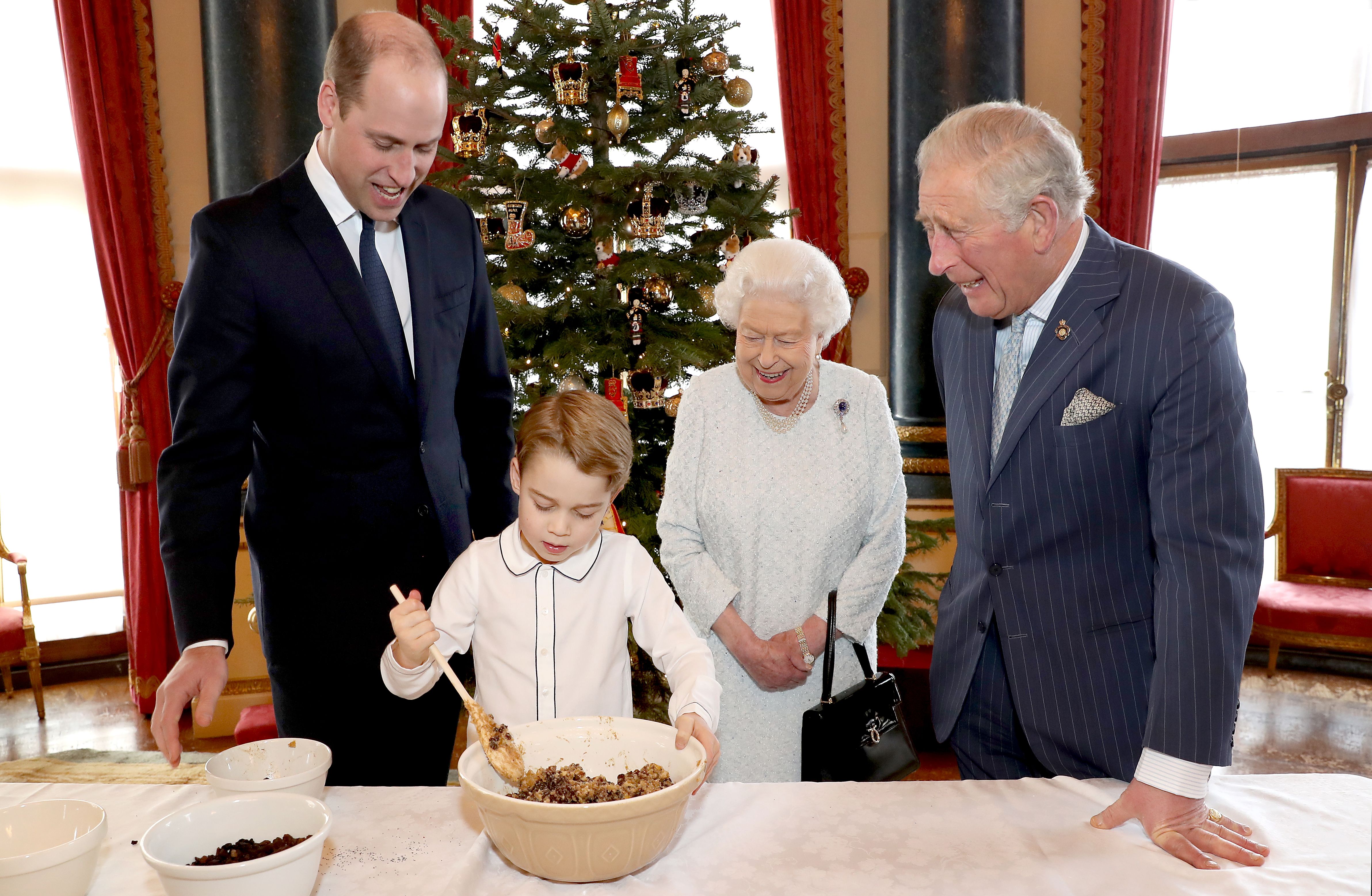 Queen Elizabeth II, Prince Charles, Prince William, and Prince George in December 2019 preparing special Christmas puddings in the Music Room at Buckingham Palace, London. | Photo: Getty Images