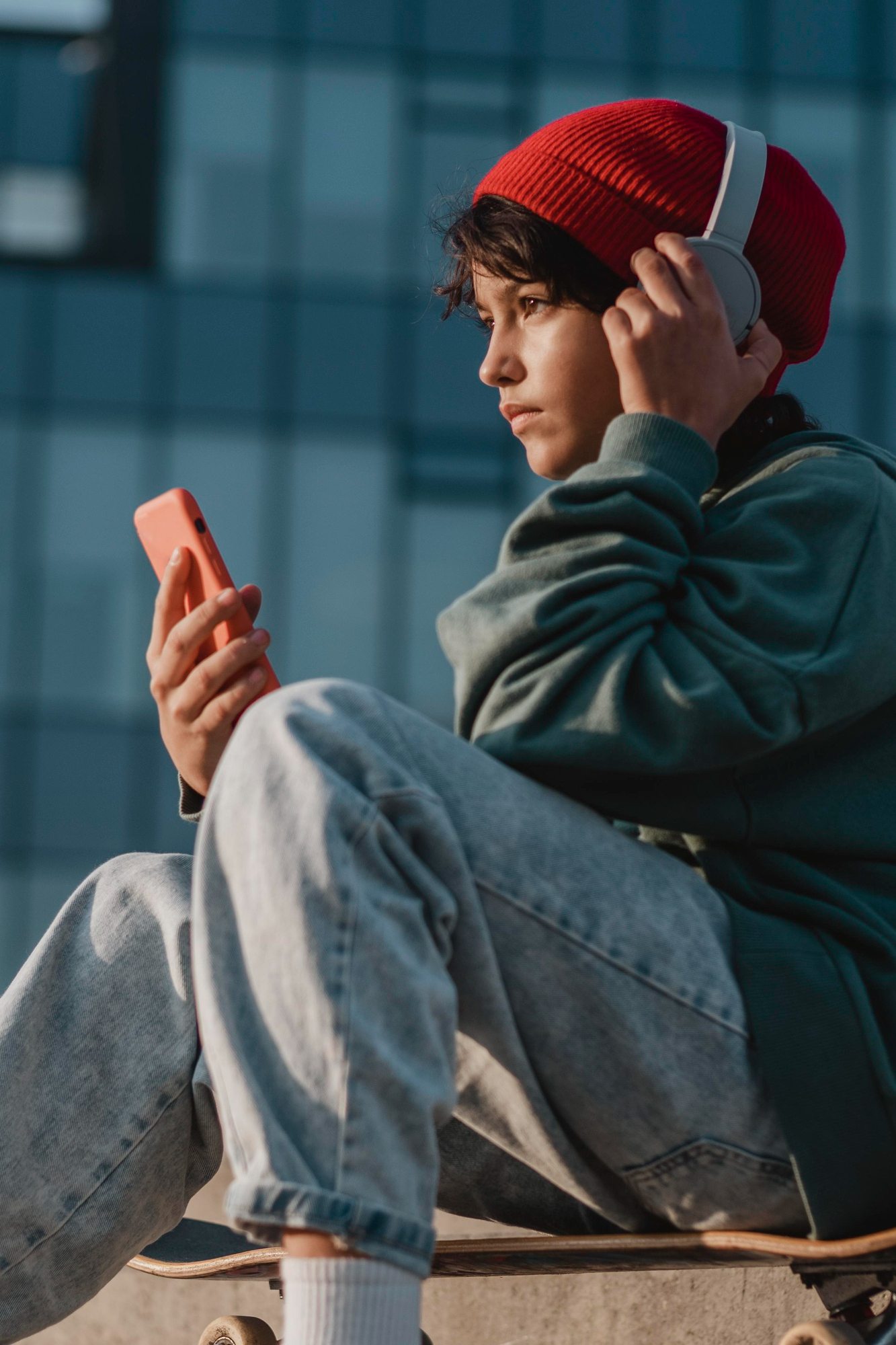 A young boy listening to something on his headsets while holding a phone | Source: Freepik