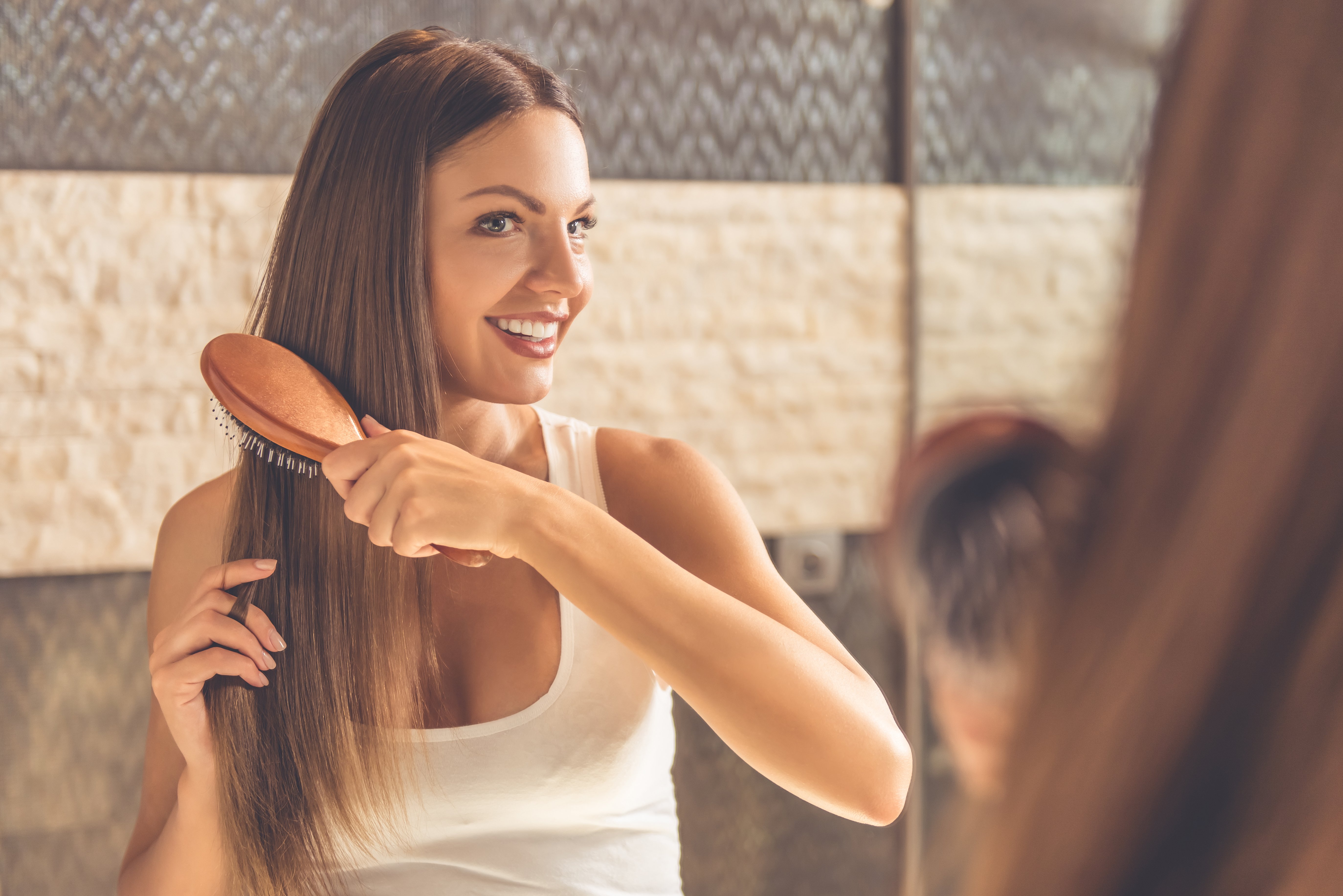 Schöne junge Frau kämmt ihre Haare | Quelle: Shutterstock