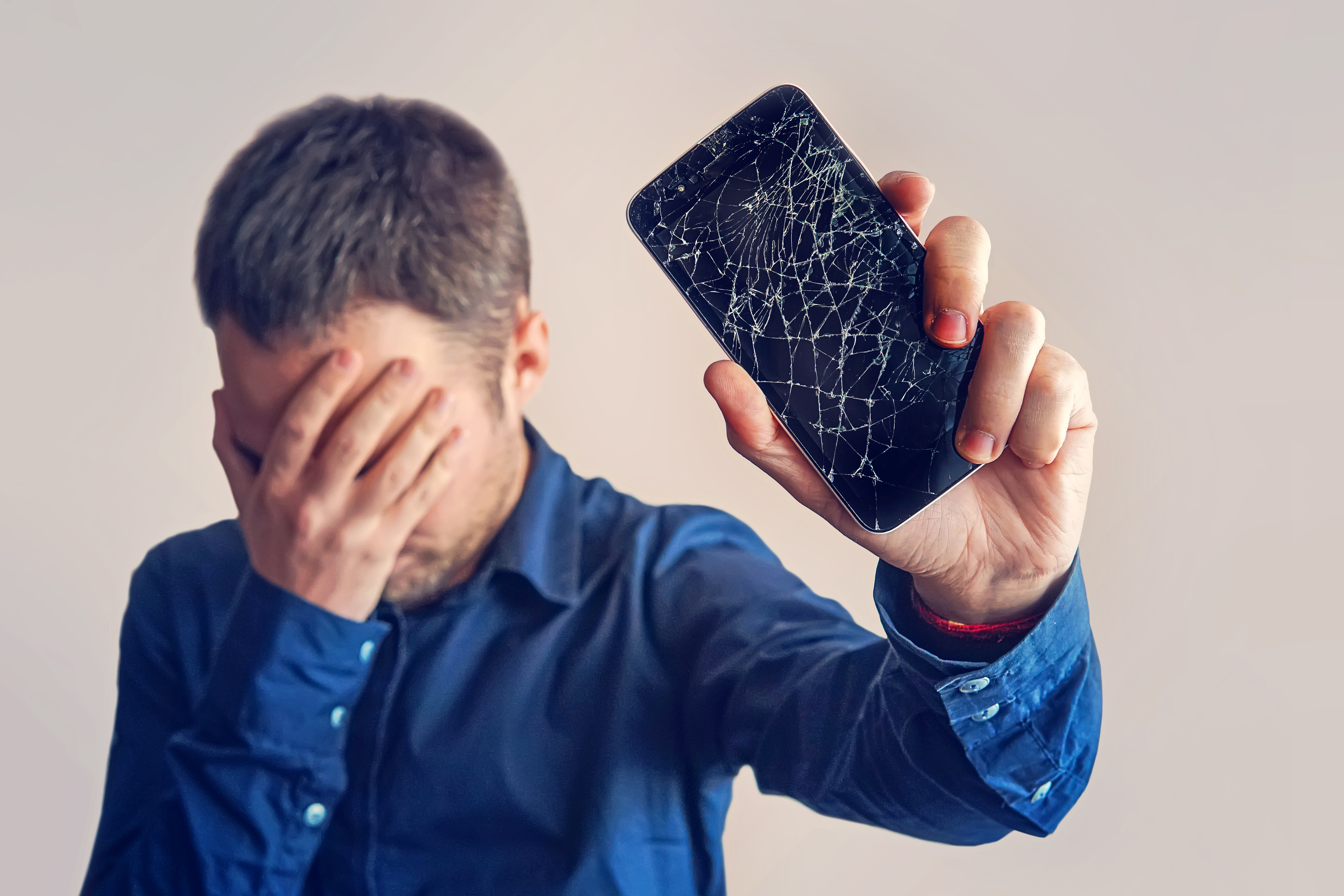 A guy holding a phone with a broken screen | Source: Shutterstock