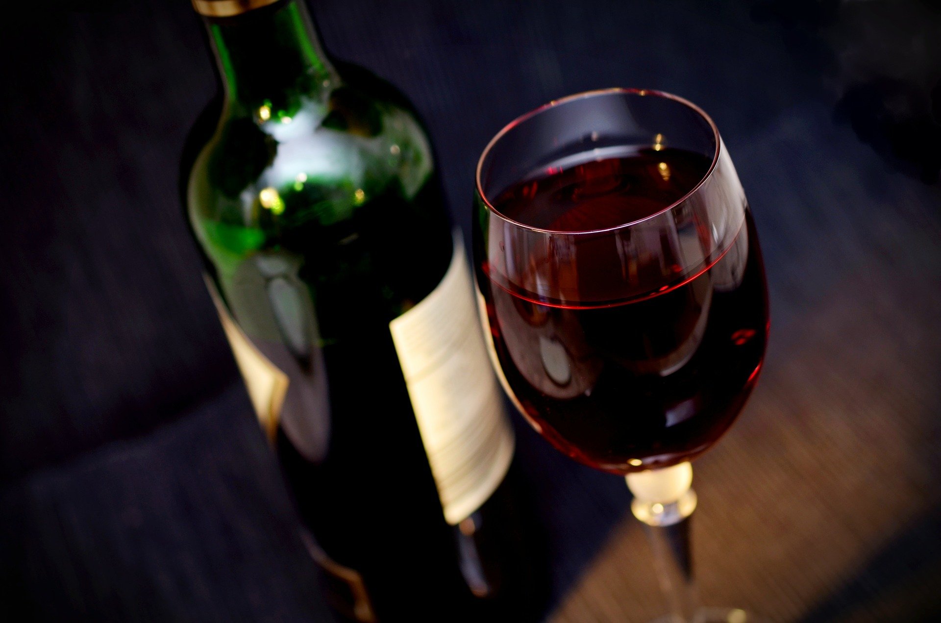 A glass of red wine alongside a wine bottle. | Photo: Pxabay/congerdesign