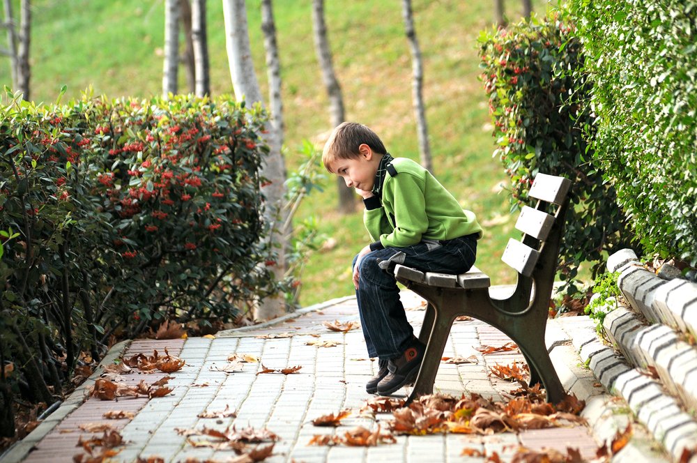 Niño sentado solo en un banco del parque. | Foto: Shutterstock