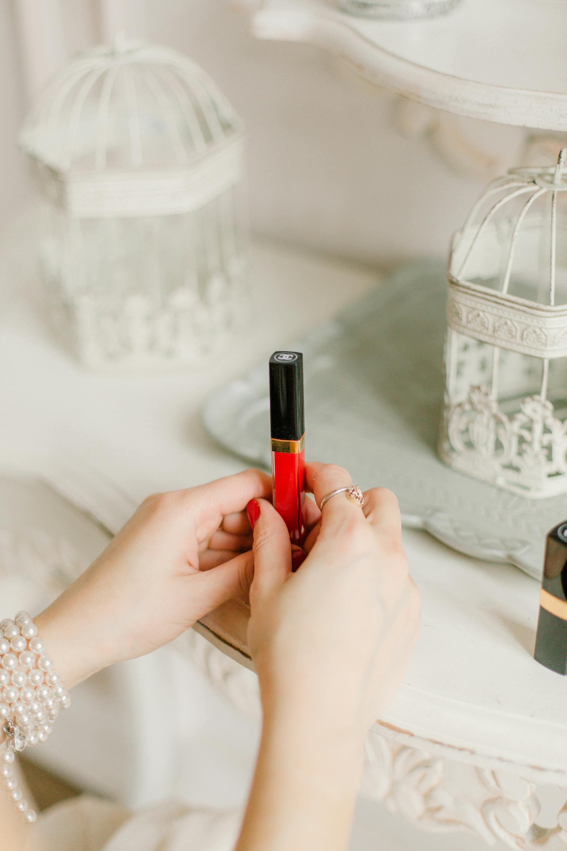 A closeup of a woman holding a red lipgloss | Source: Pexels