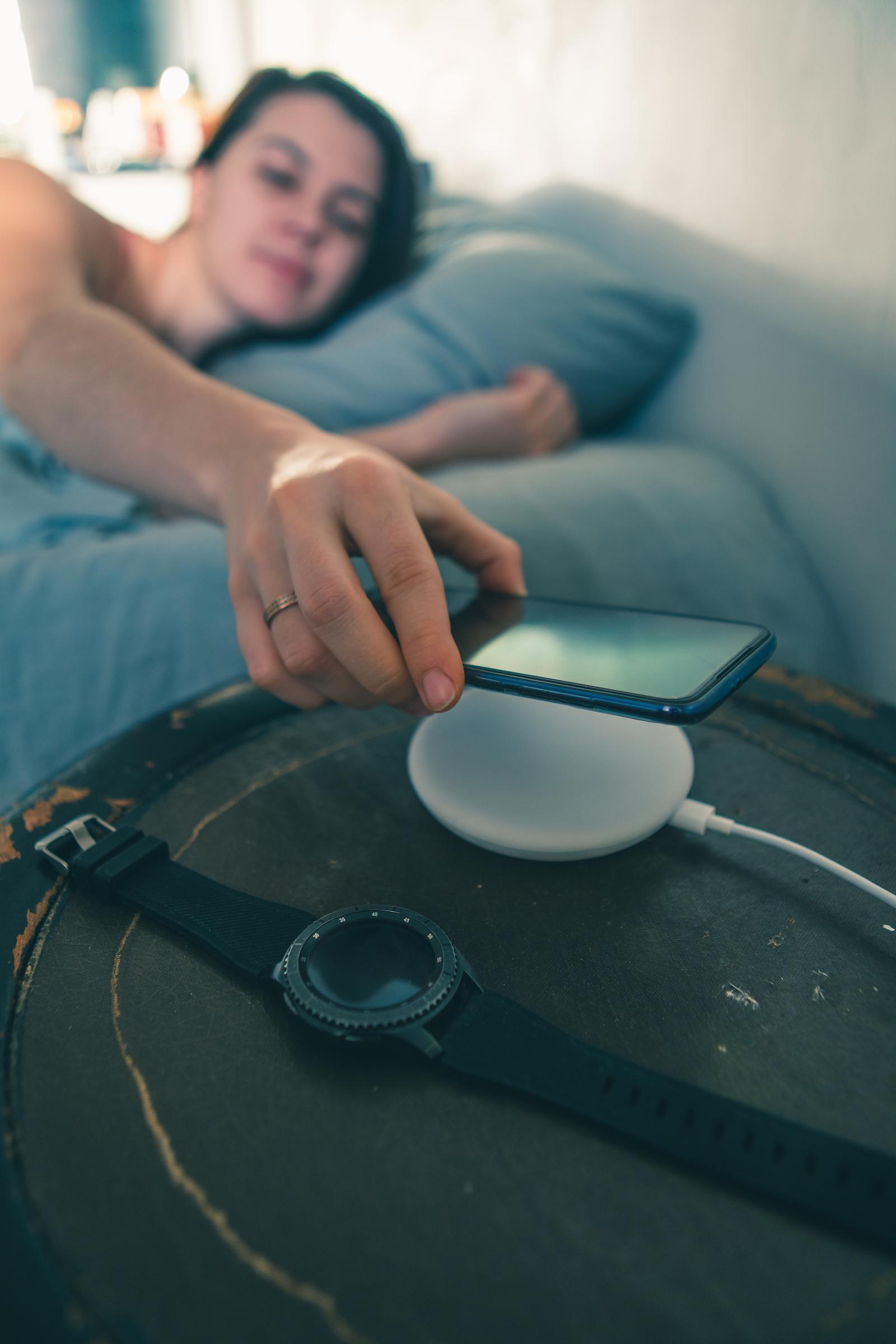 Woman placing her cellphone on her bedside table | Source: Shutterstock