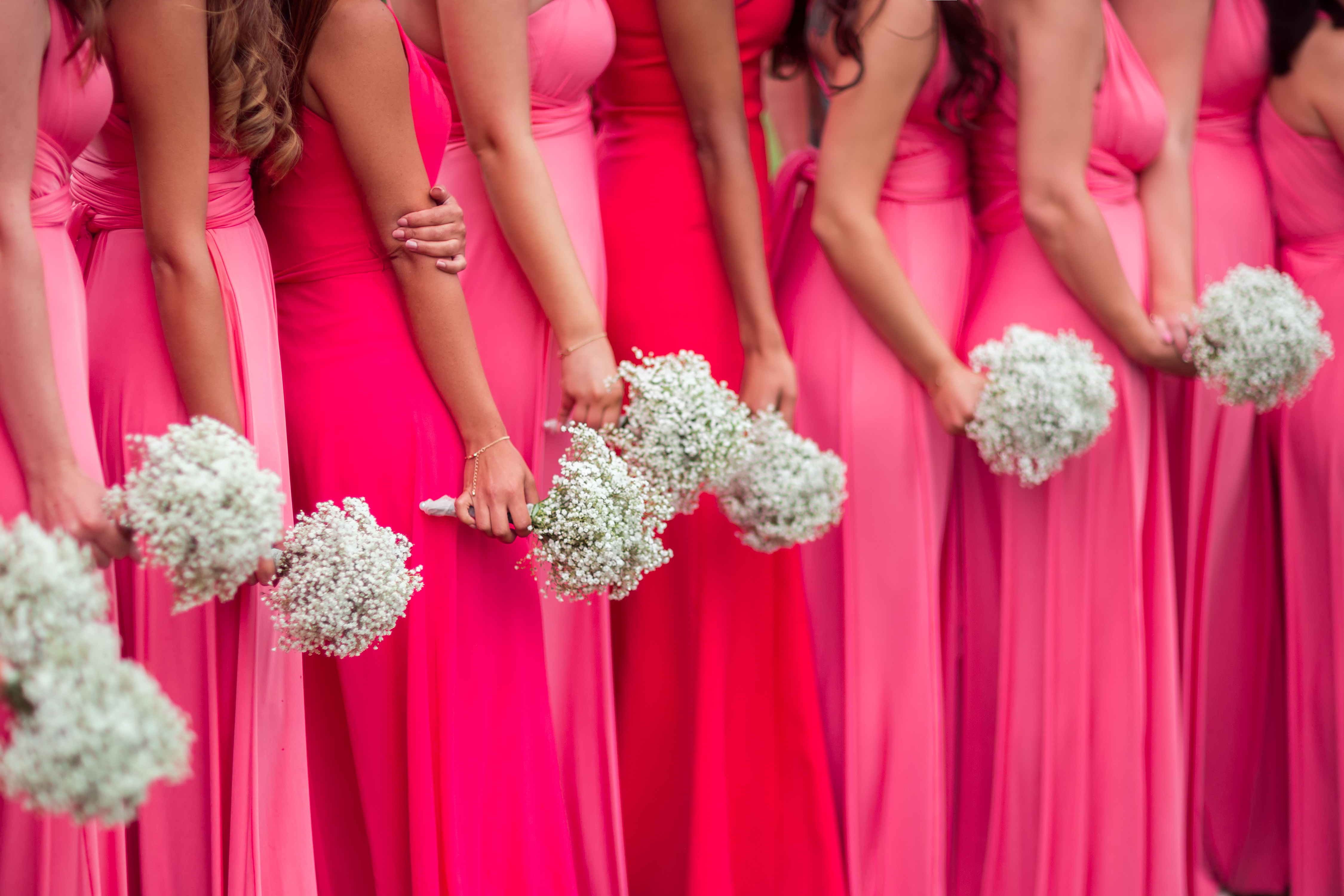 A row of bridesmaids in pink, each carrying a flower bouquet | Source: Shutterstock