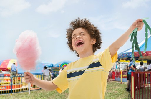 Photo of a young boy with cotton candy and prize tickets at fair  | Photo: Getty Images