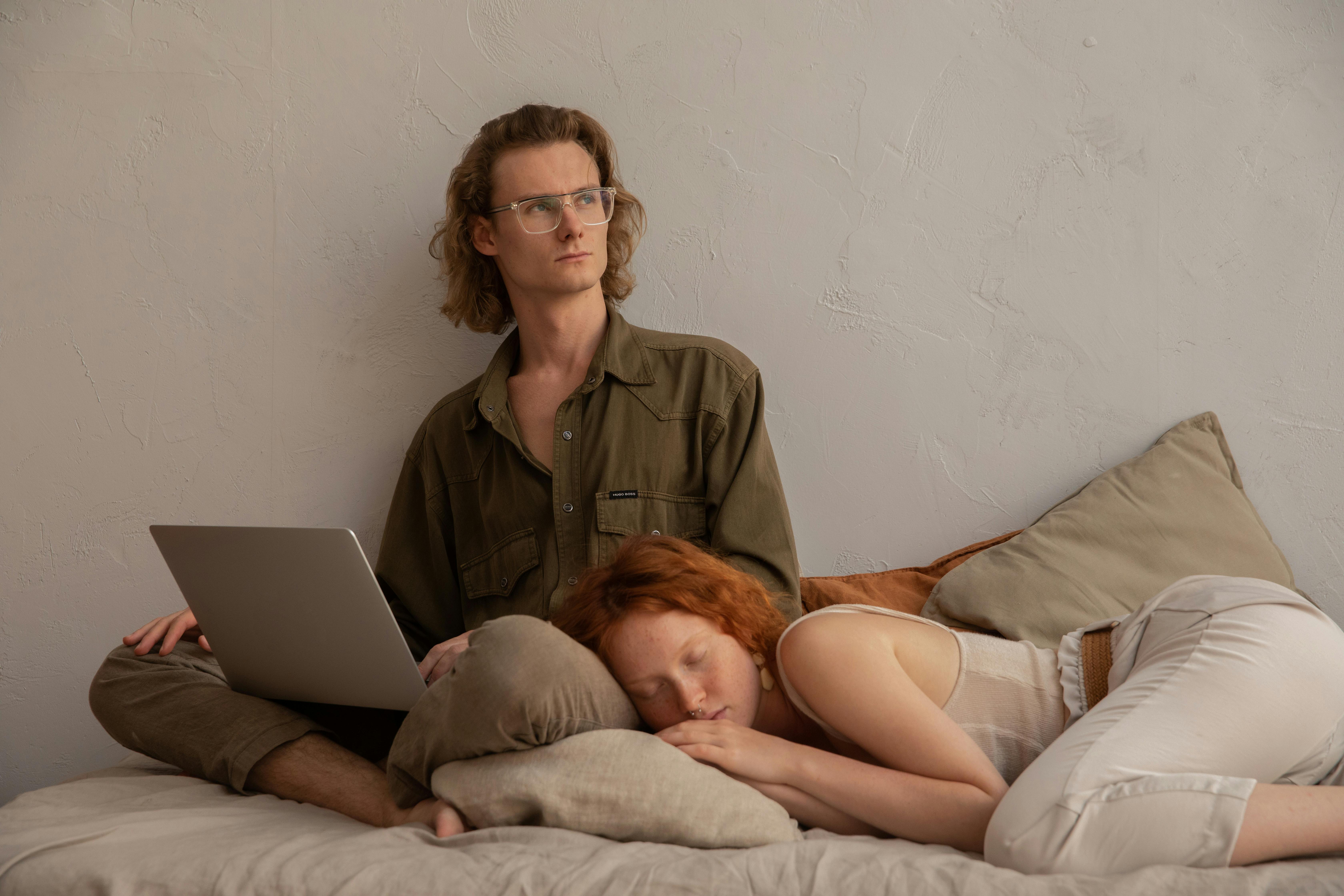 Man looks to the side while a woman sleeps next to him | Source: Pexels