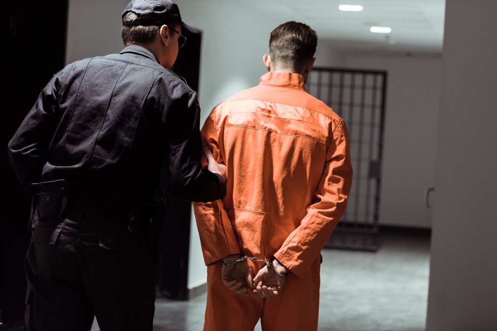 A rear view of prison officer leading prisoner out of his cell. | Photo: Shutterstock