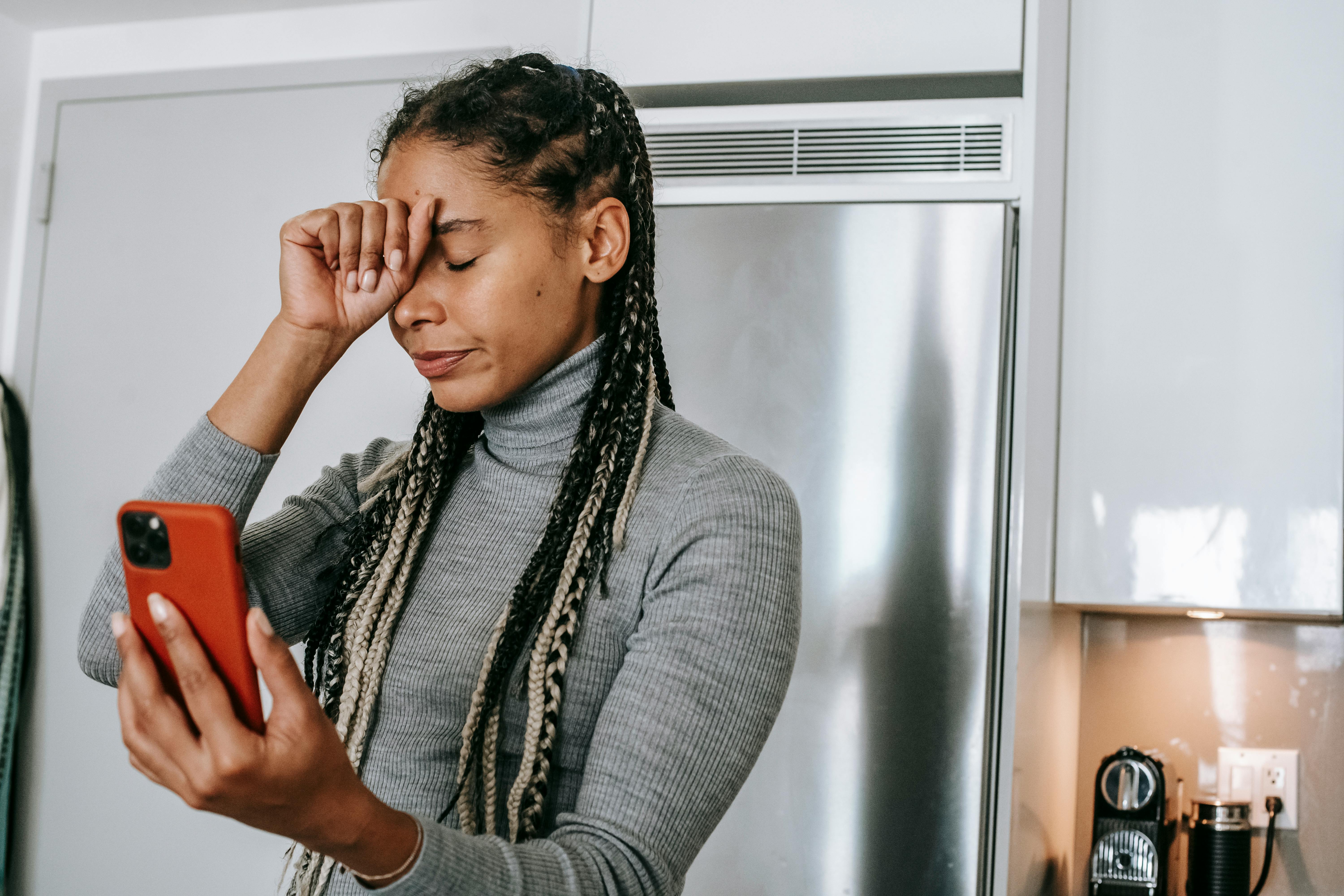 An upset woman with her hand on her forehead while holding a phone | Source: Pexels