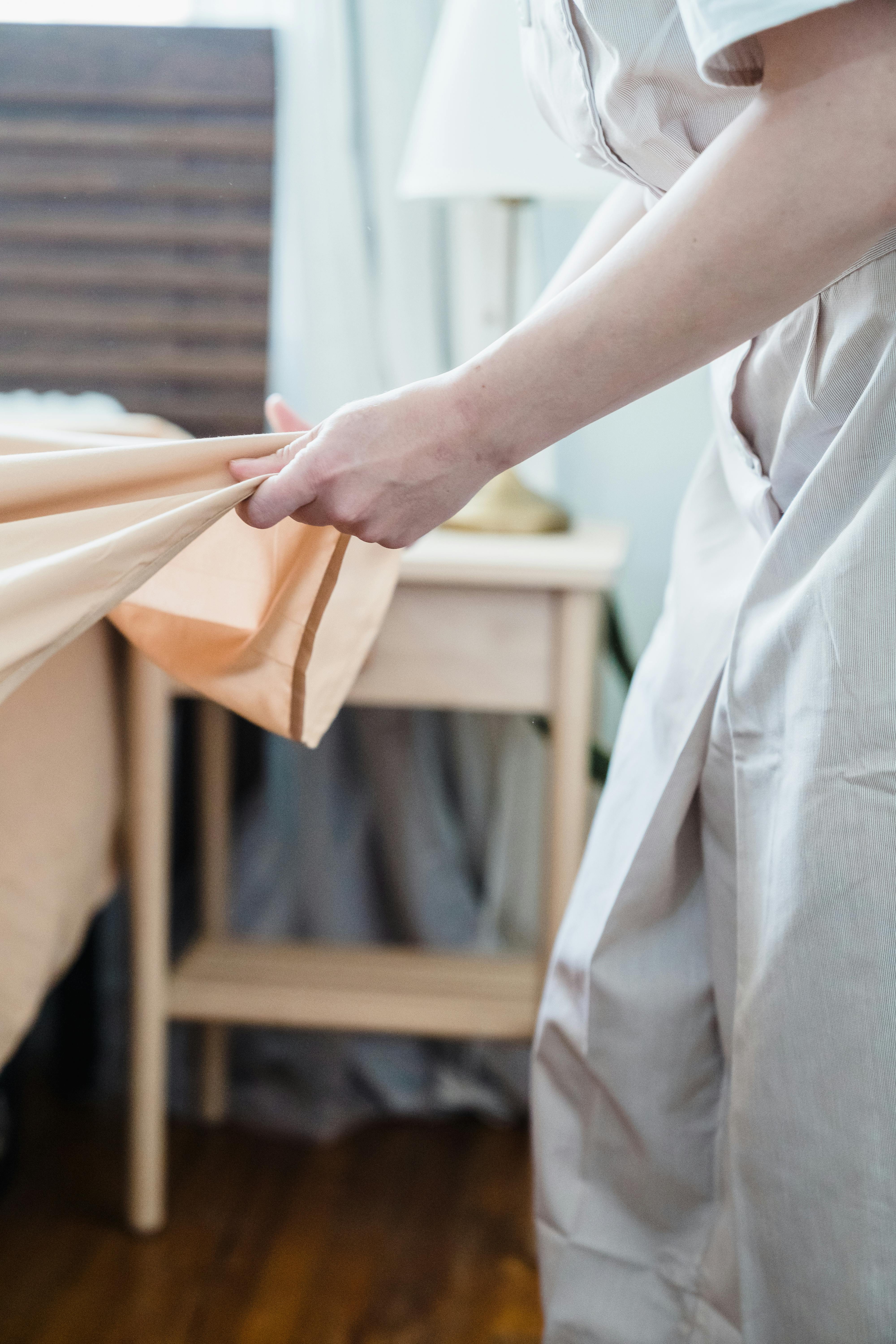 A woman folding a sheet | Source: Pexels